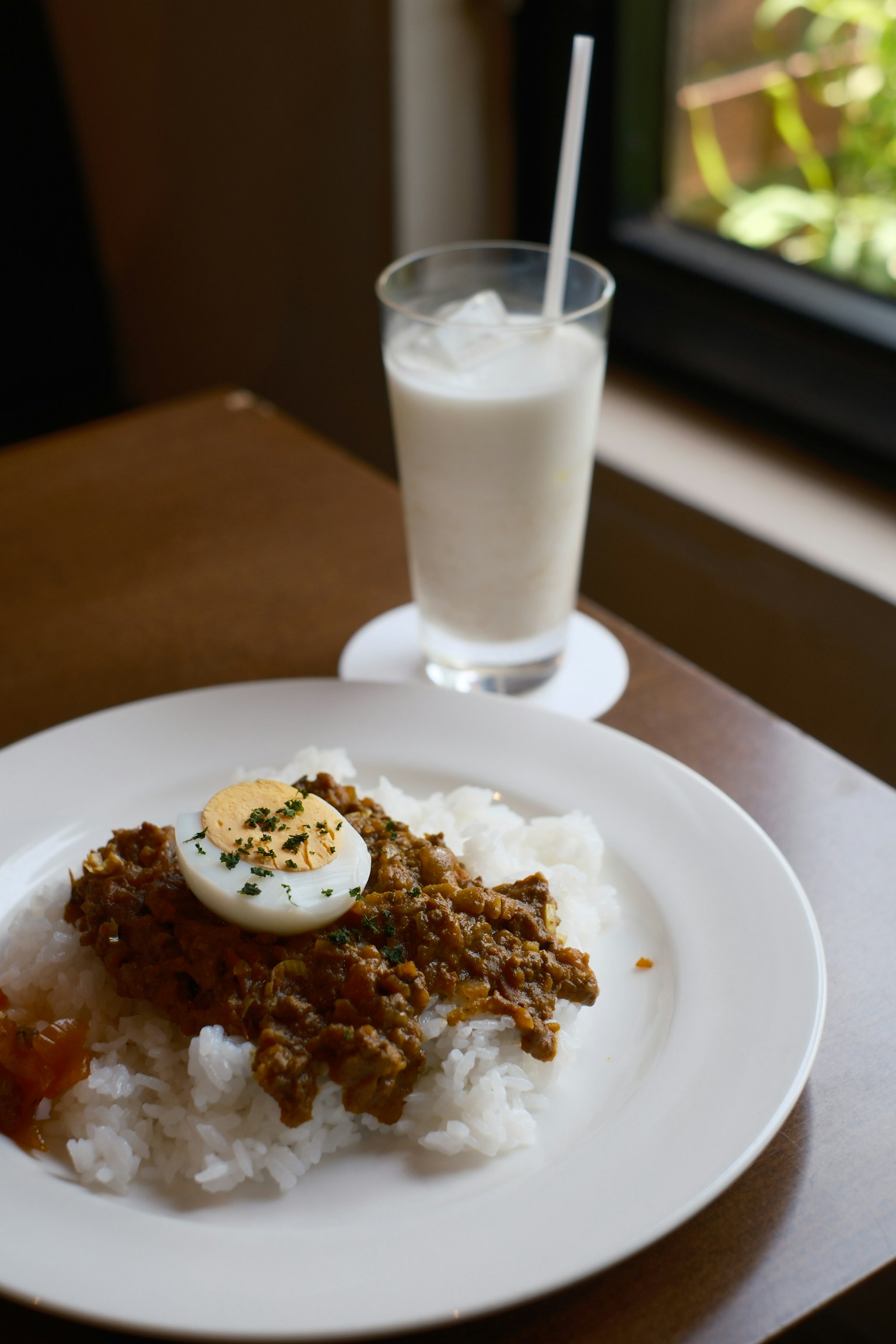白ご飯の上に揚げた鶏肉と半熟卵が載った料理と飲み物