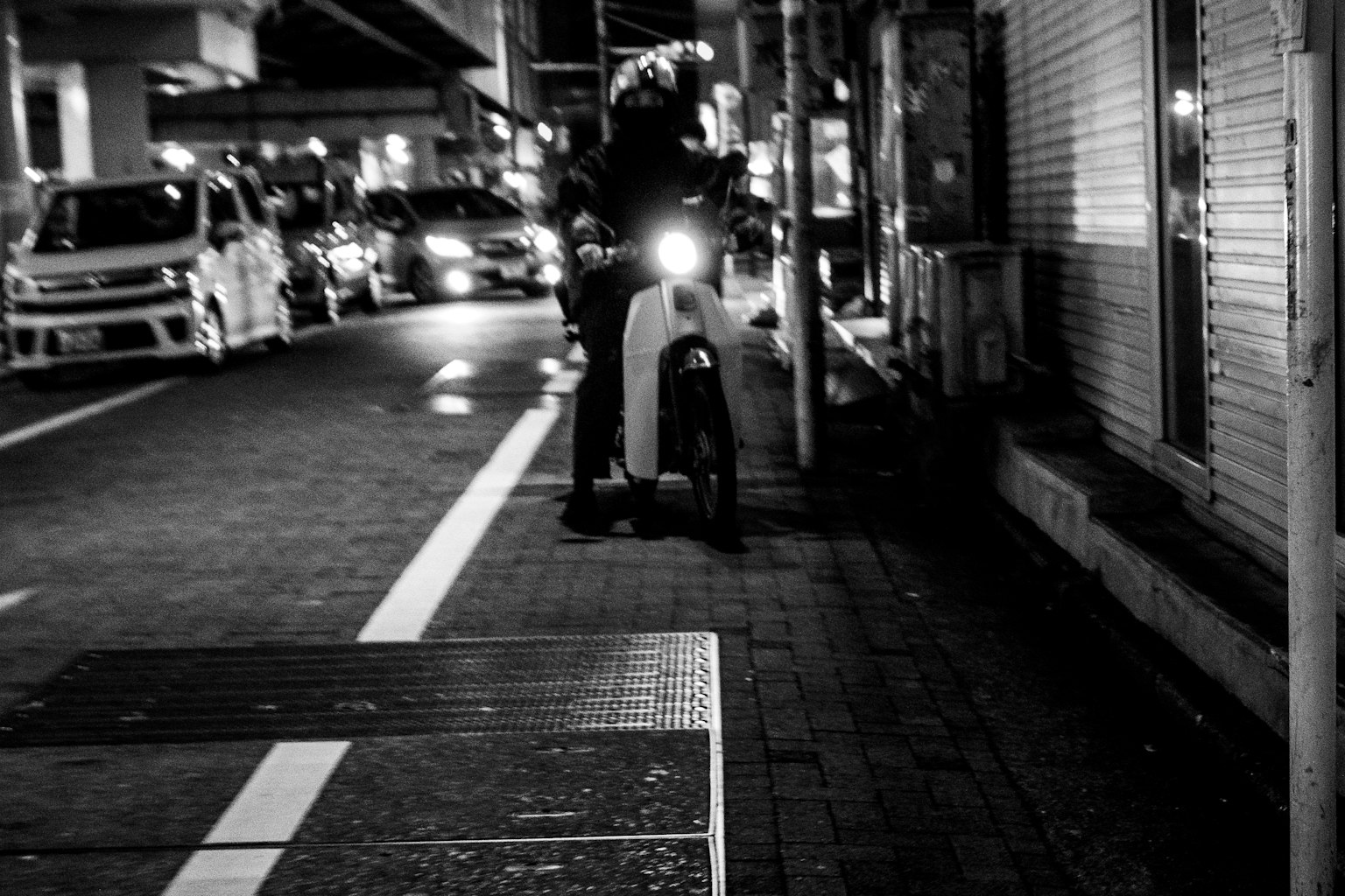 Motorcycle parked on a city street at night with a line of cars