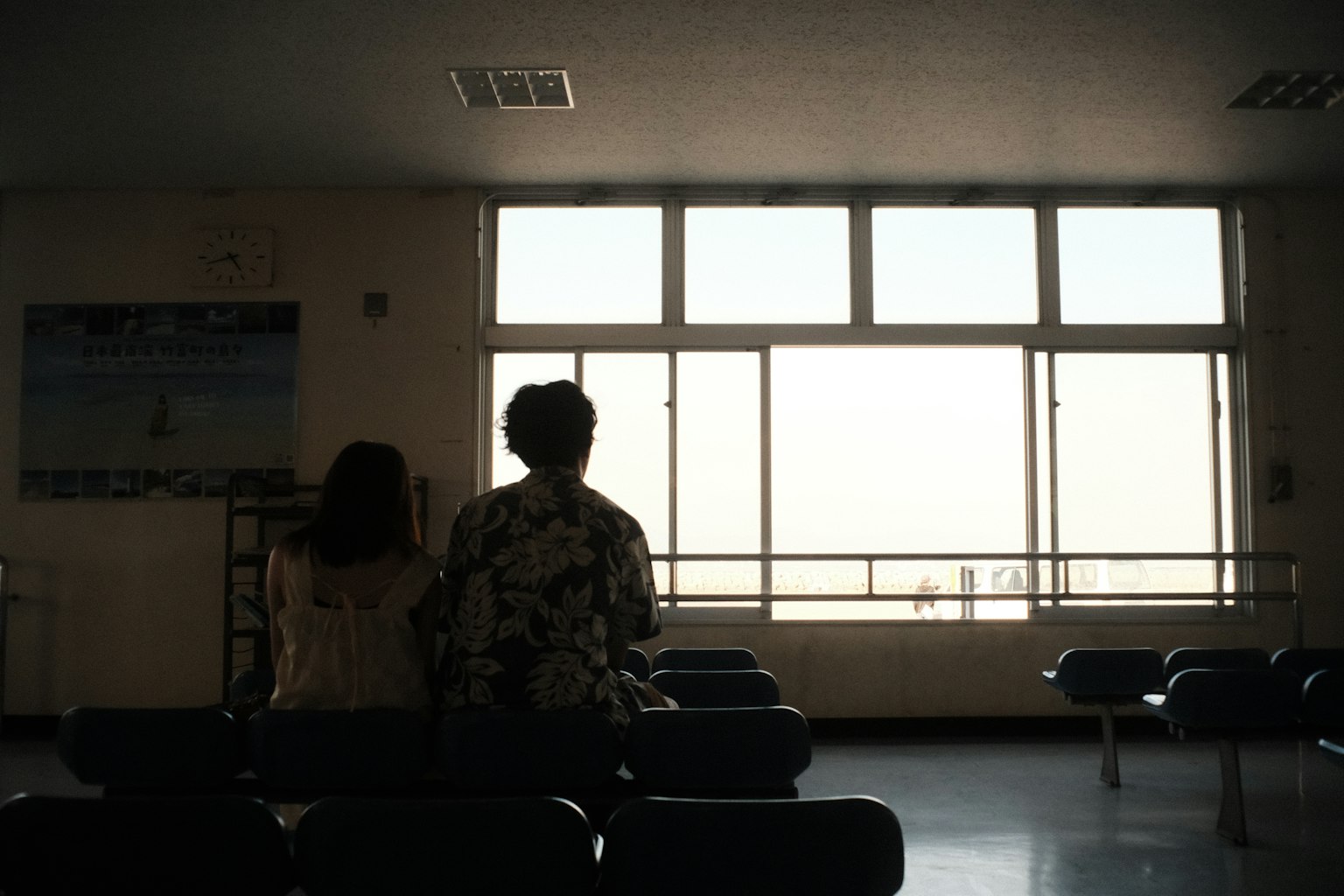 Due figure che guardano fuori da una finestra in una sala d'attesa silenziosa