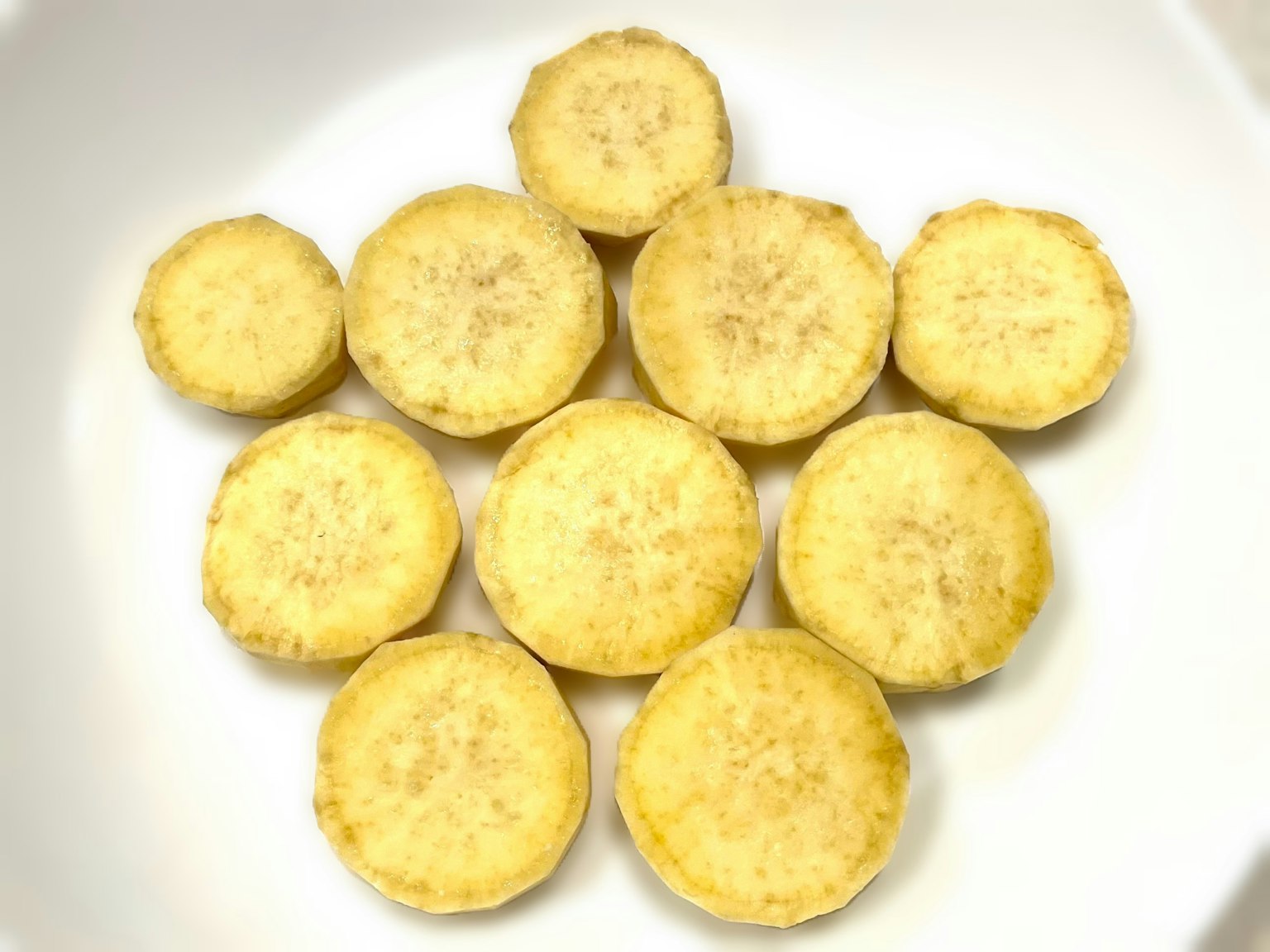 Bananes jaunes tranchées disposées sur une assiette blanche