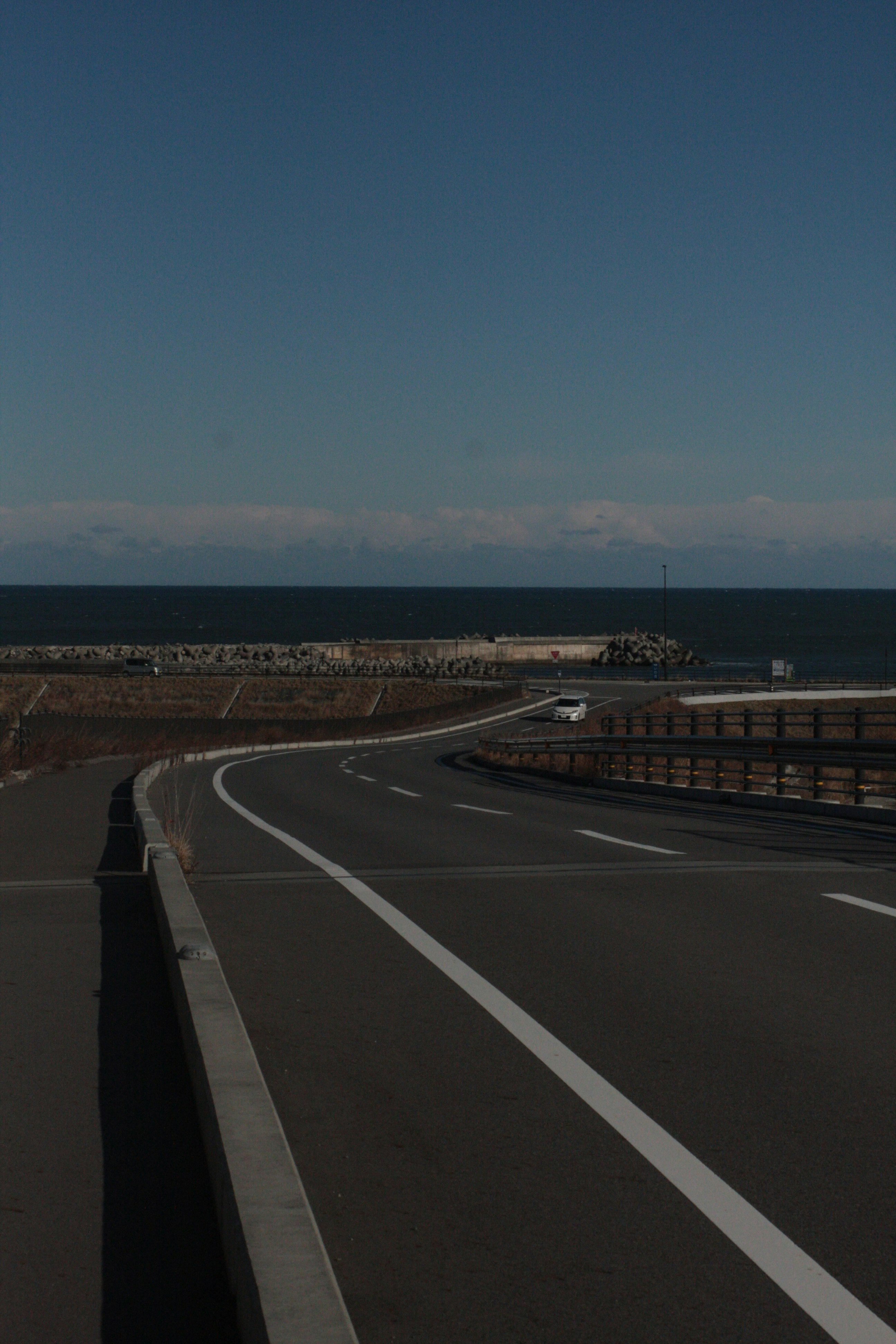 海沿いの道路と防波堤のある夕暮れの風景