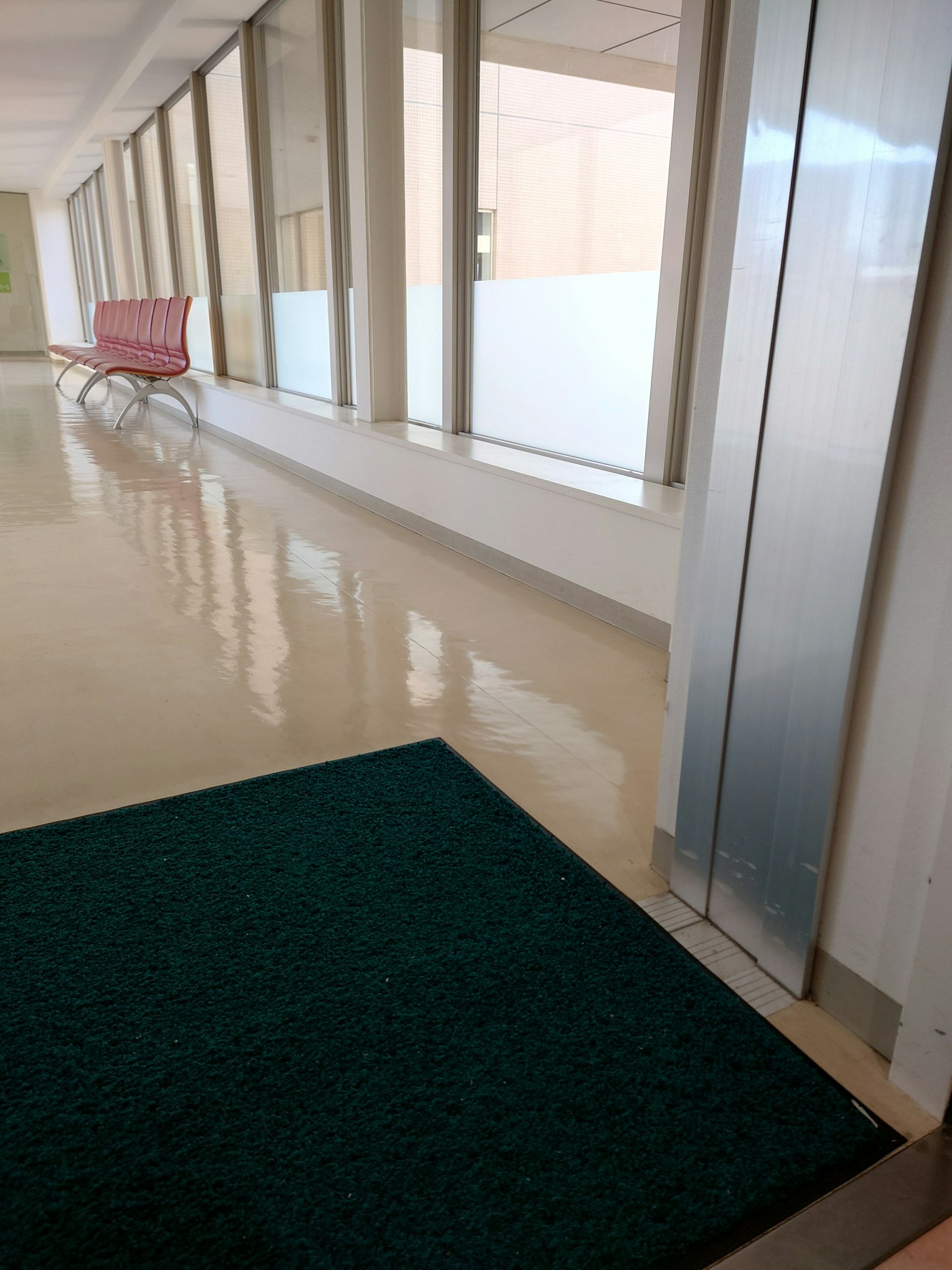 Heller Flur mit grünem Teppich und roter Bank