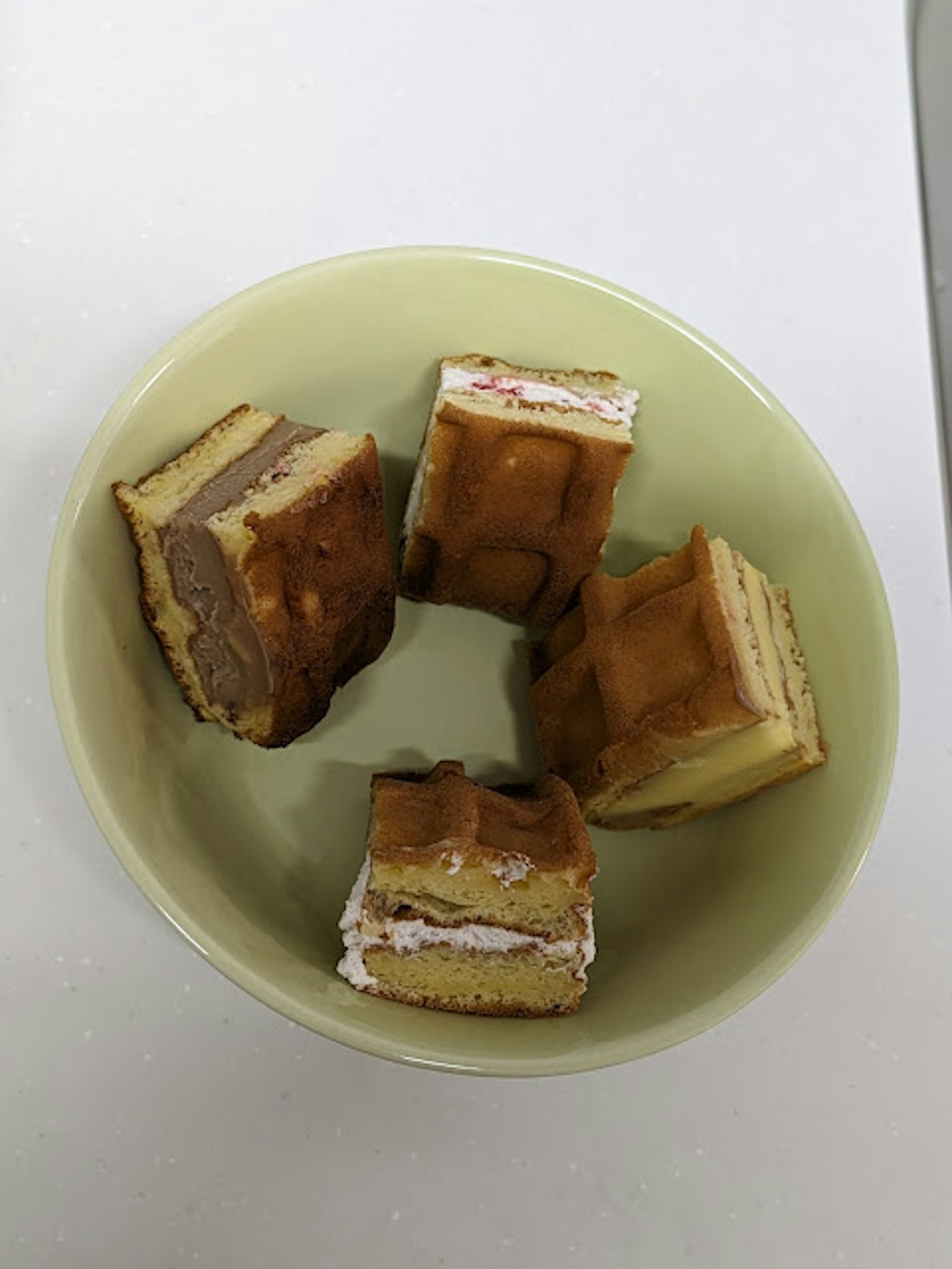 Vier Stücke Schichtkuchen in einer grünen Schüssel