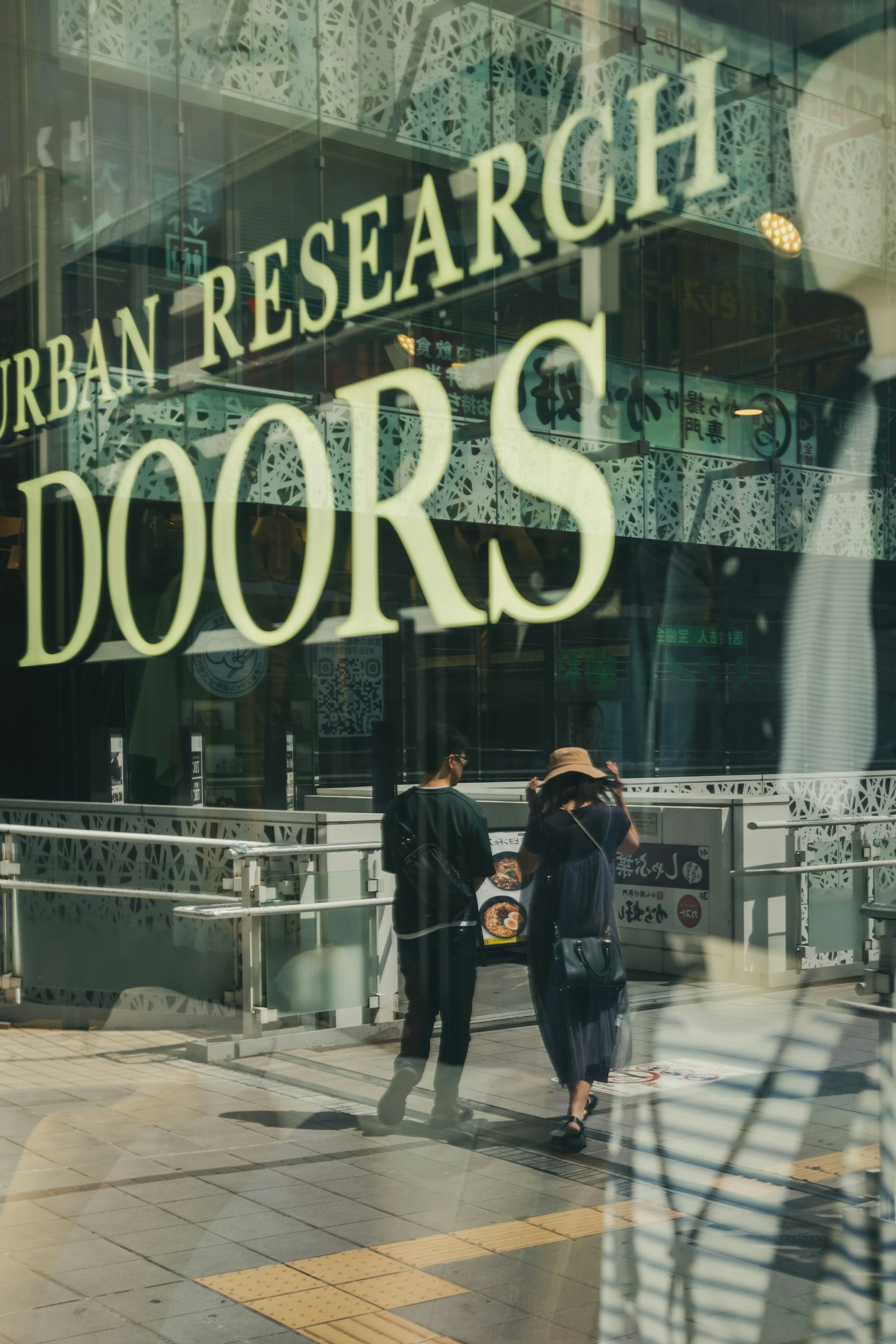 映出两个人在Urban Research门前走过的倒影