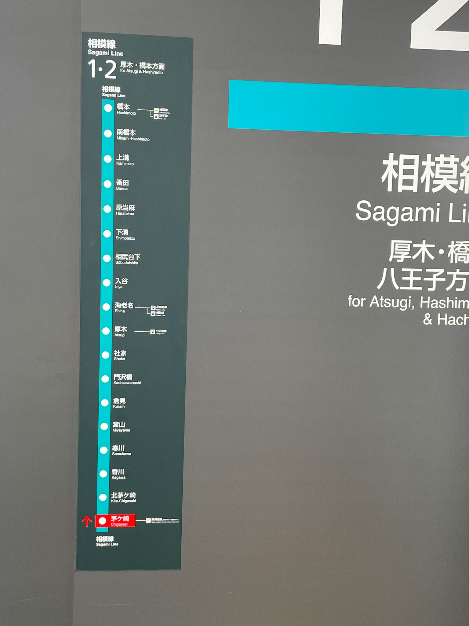 Schild mit den Stationsnamen und Fahrplan für die Sagami-Linie