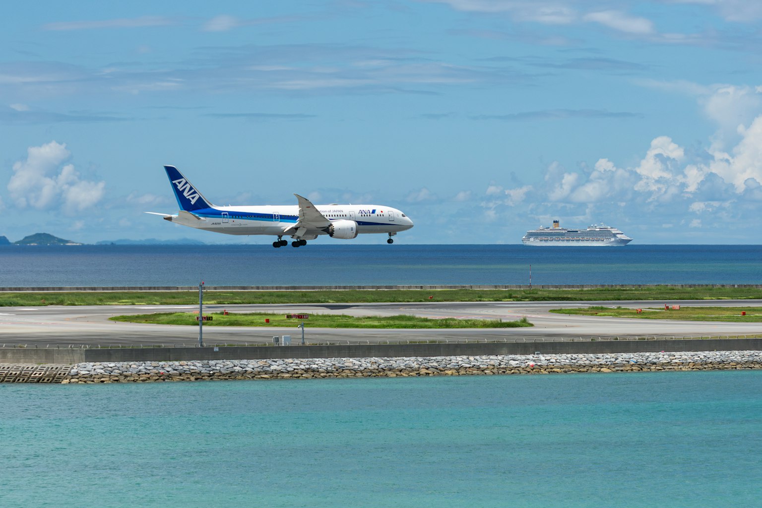 青い海と空の背景に飛行機が着陸する様子とクルーズ船が浮かぶ風景