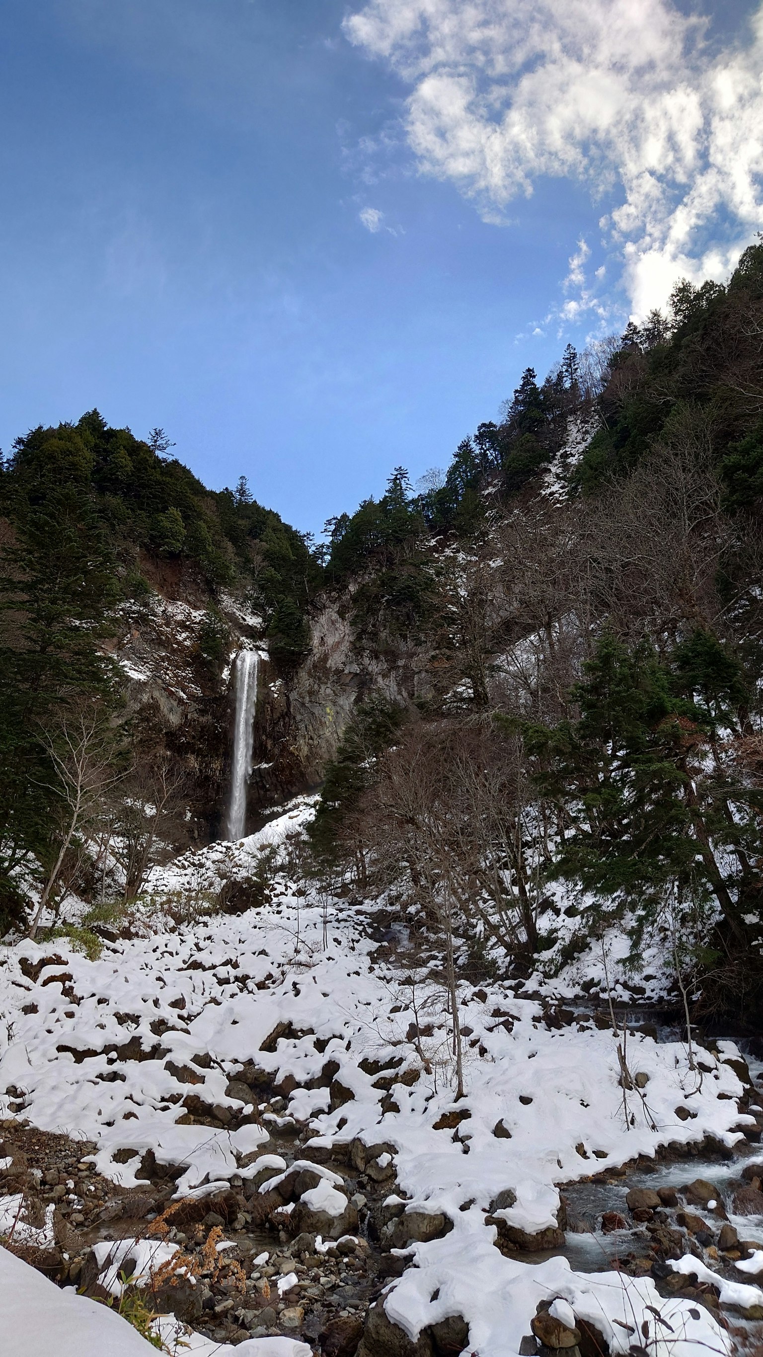 被雪覆盖的山脉和瀑布 蓝天和白云