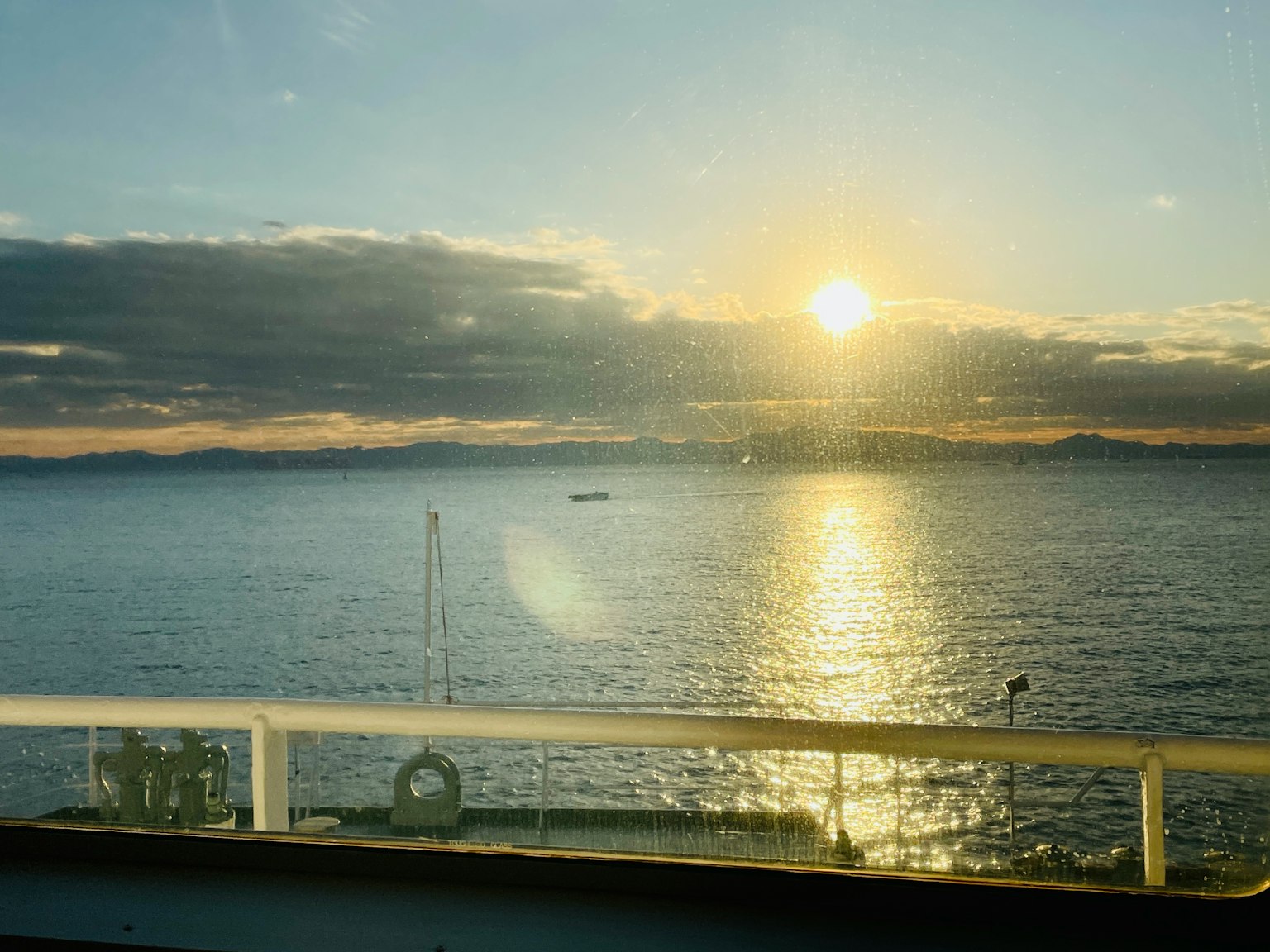 Alba sul mare con acque calme e montagne lontane
