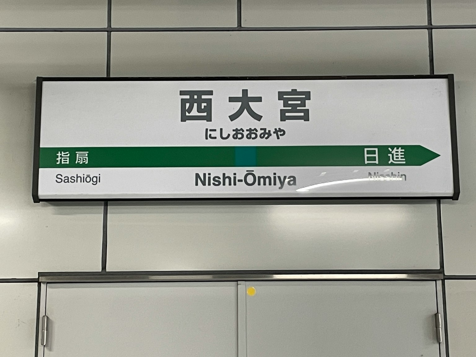 Biển chỉ dẫn cho ga Nishi-Omiya với mũi tên màu xanh chỉ hướng
