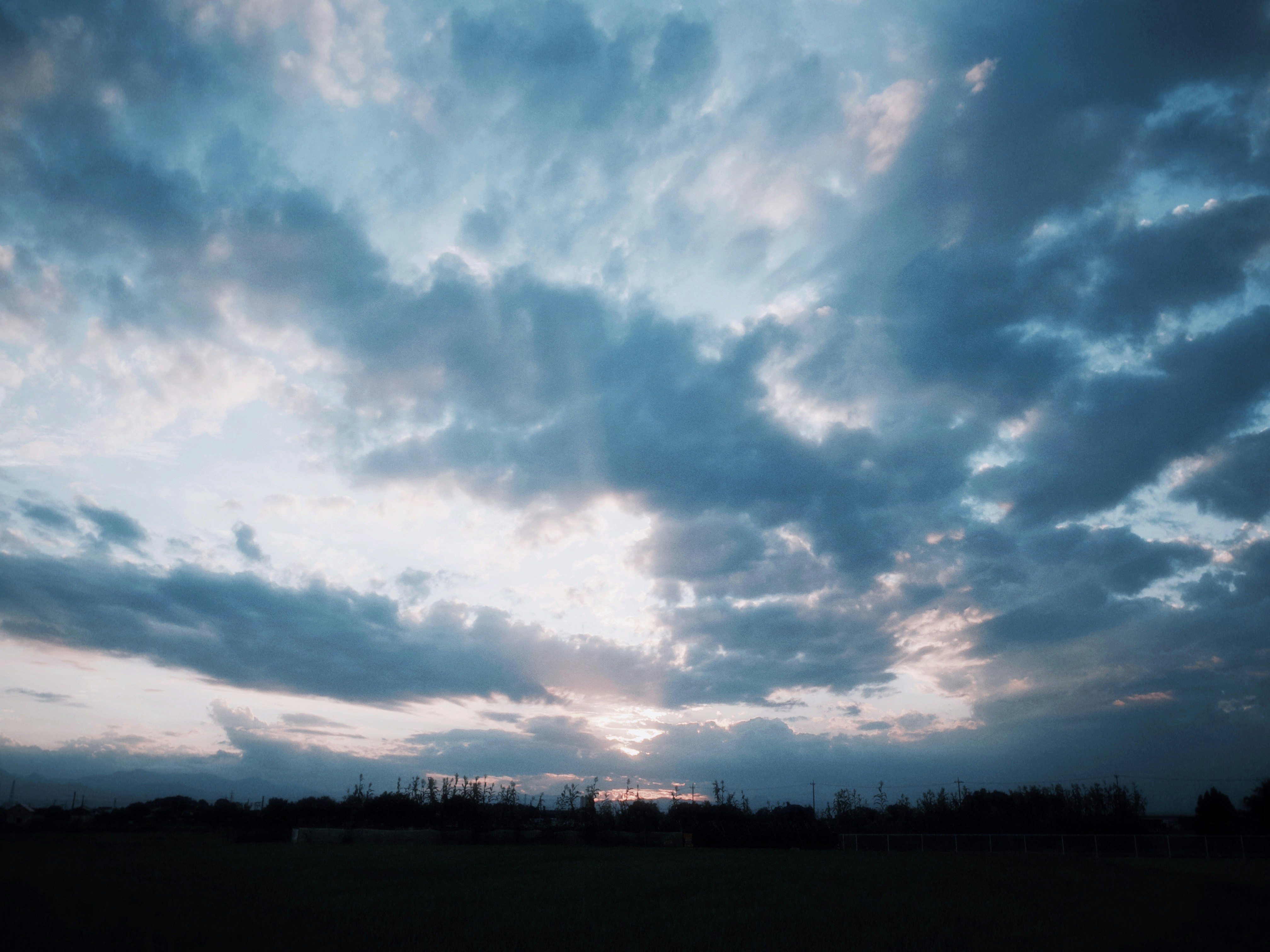 grand ciel de fin de journée avec nuages superposés au-dessus d’un champ d’herbe