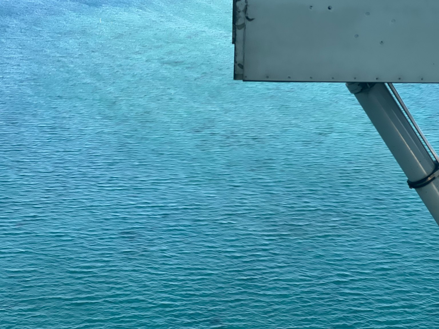 Blick auf die blaue Wasseroberfläche des Ozeans mit einem Teil eines Bootes
