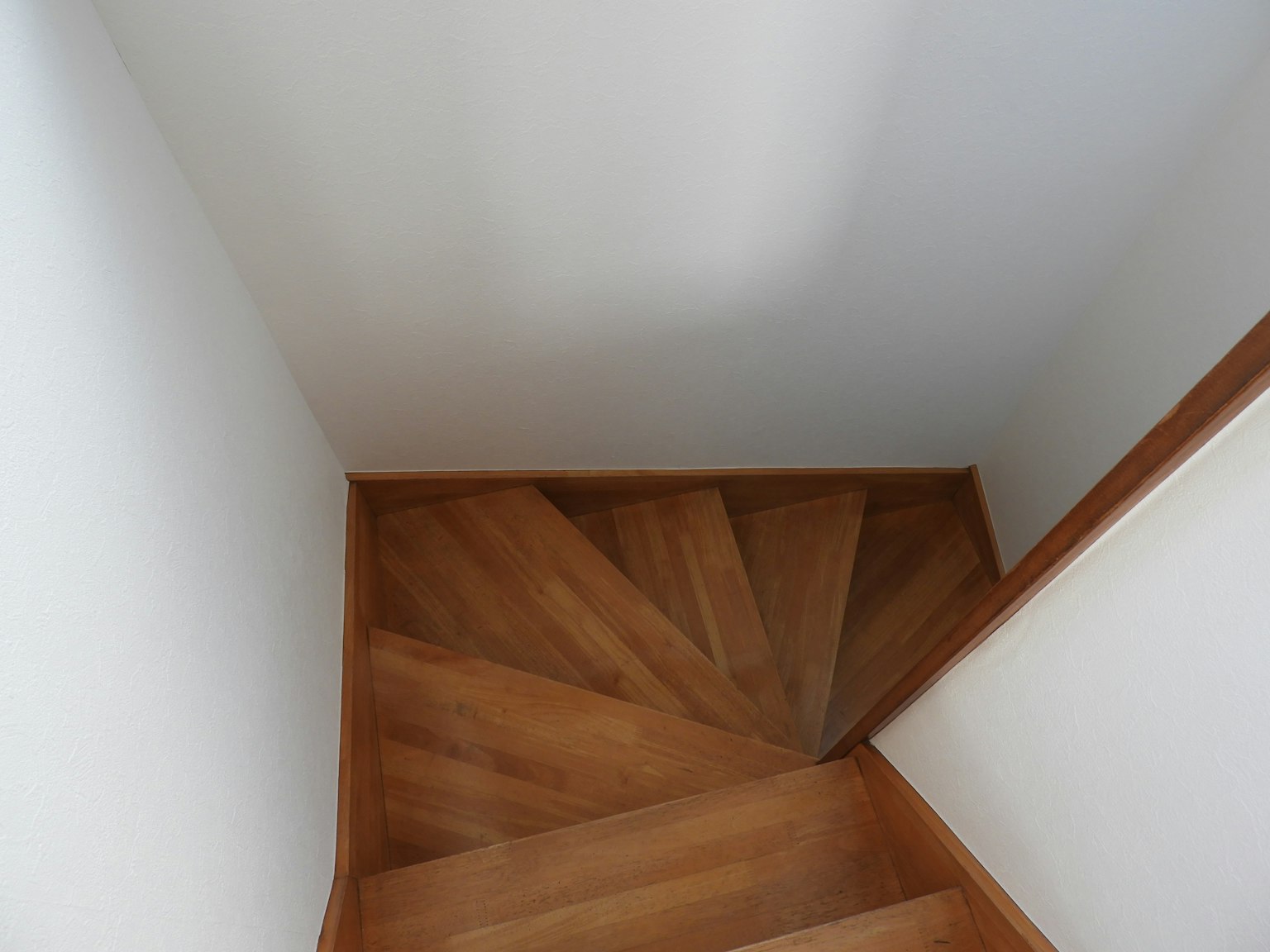 View of a wooden spiral staircase with light walls
