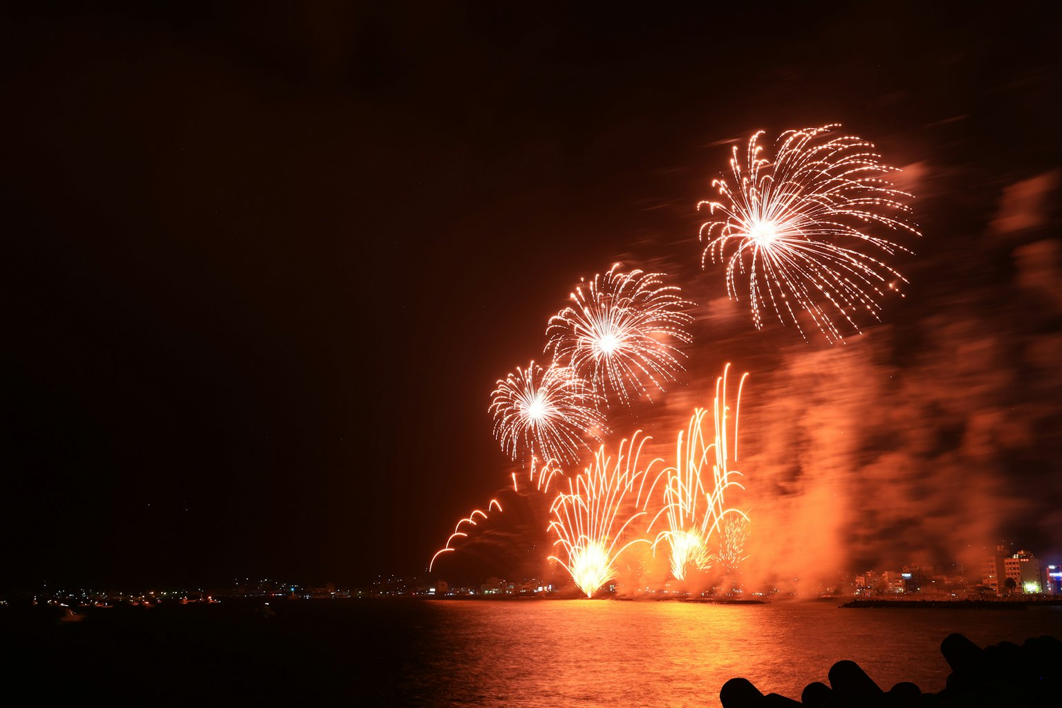 Spettacolo di fuochi d'artificio vivaci sull'acqua di notte