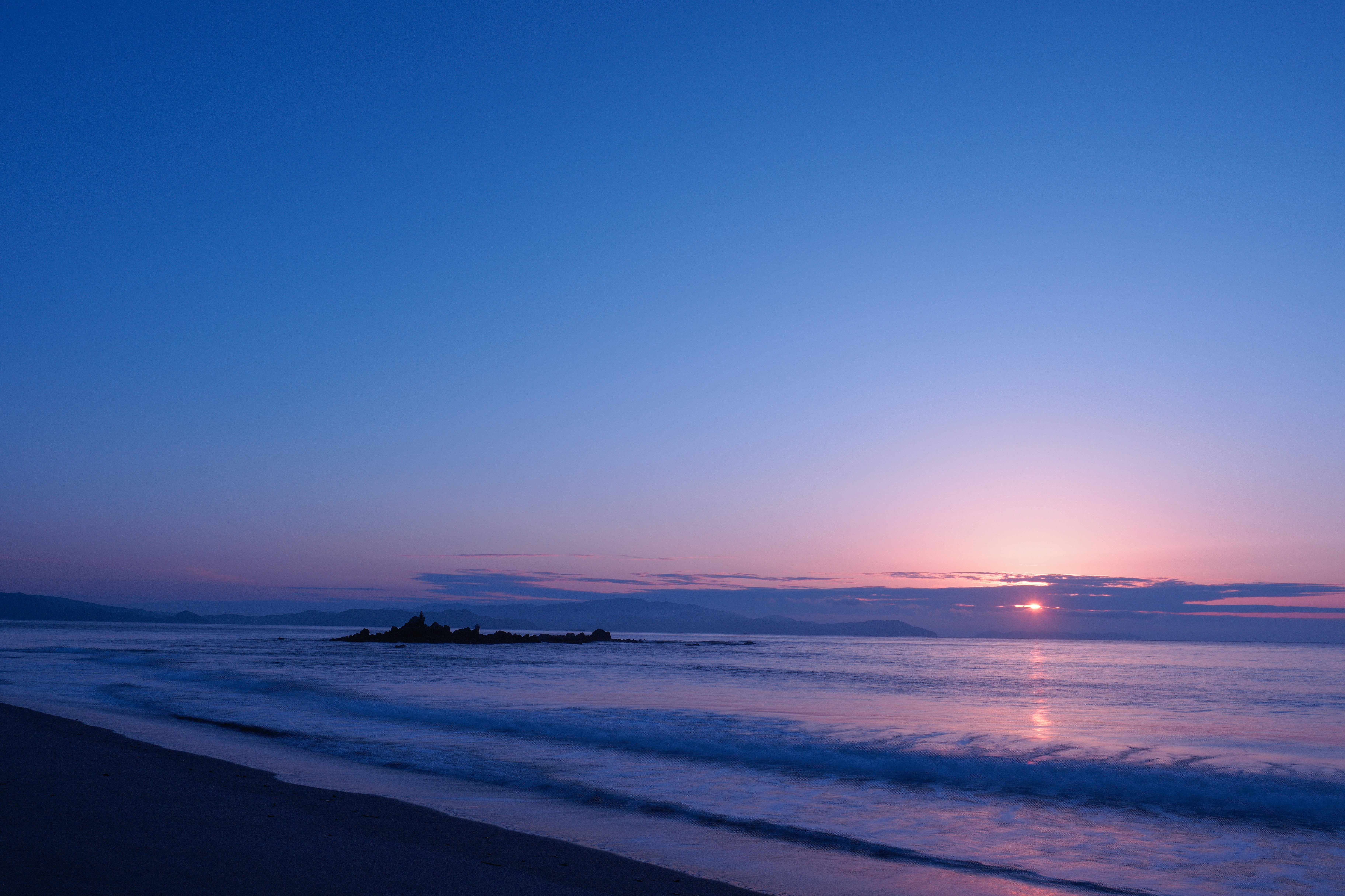 穏やかな海辺に差し込む優しい朝日