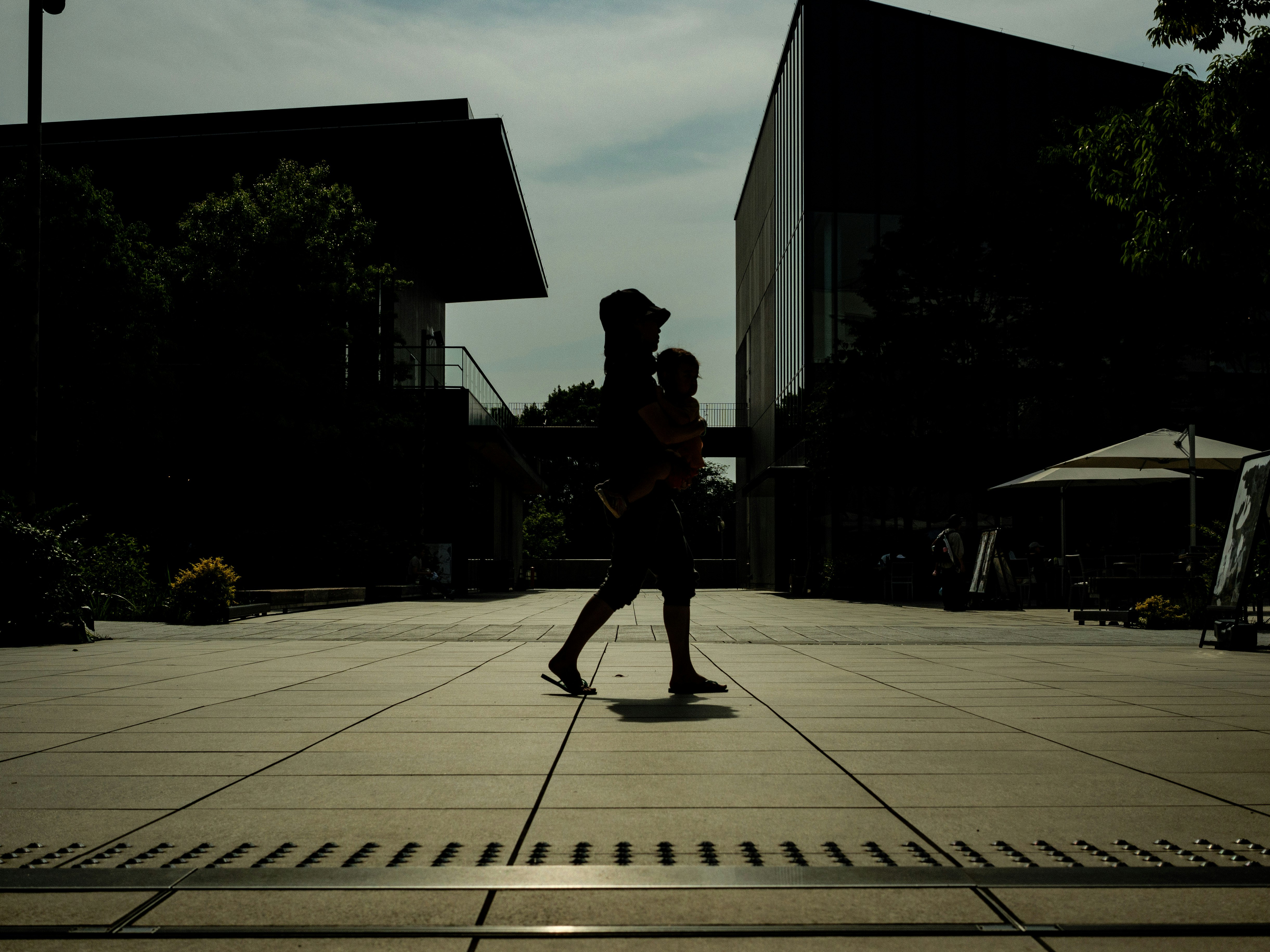 parent and child running across an outdoor plaza at dusk