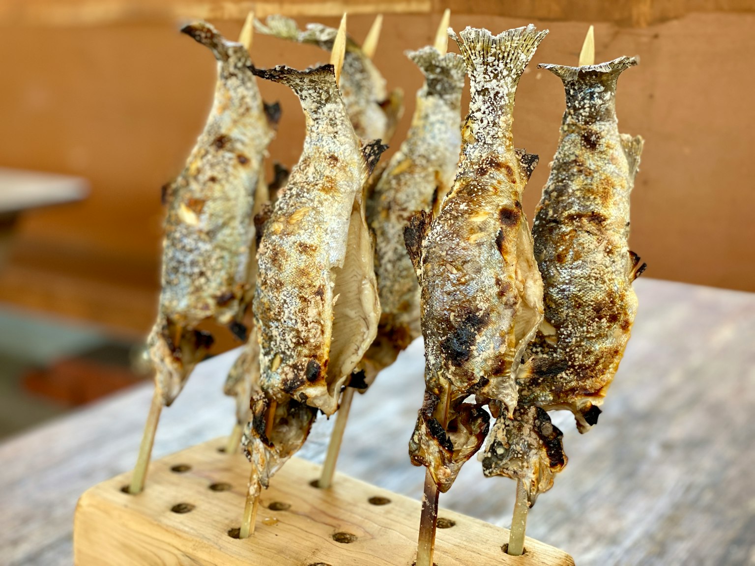 Brochetas de pescado a la parrilla en un soporte de madera