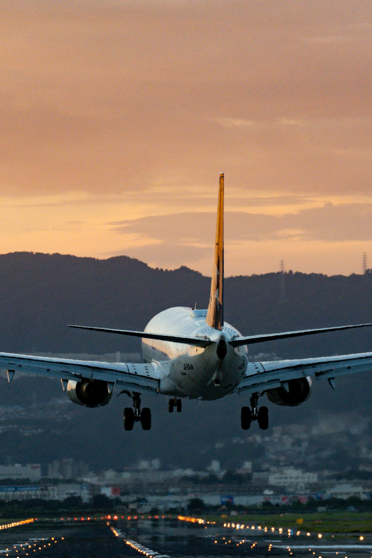 Avion atterrissant au coucher du soleil avec des montagnes en arrière-plan