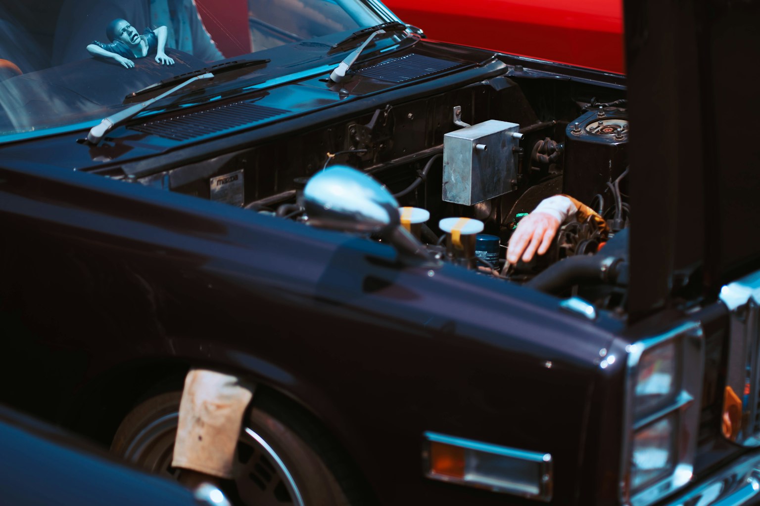 Hand working in the engine compartment of a black car