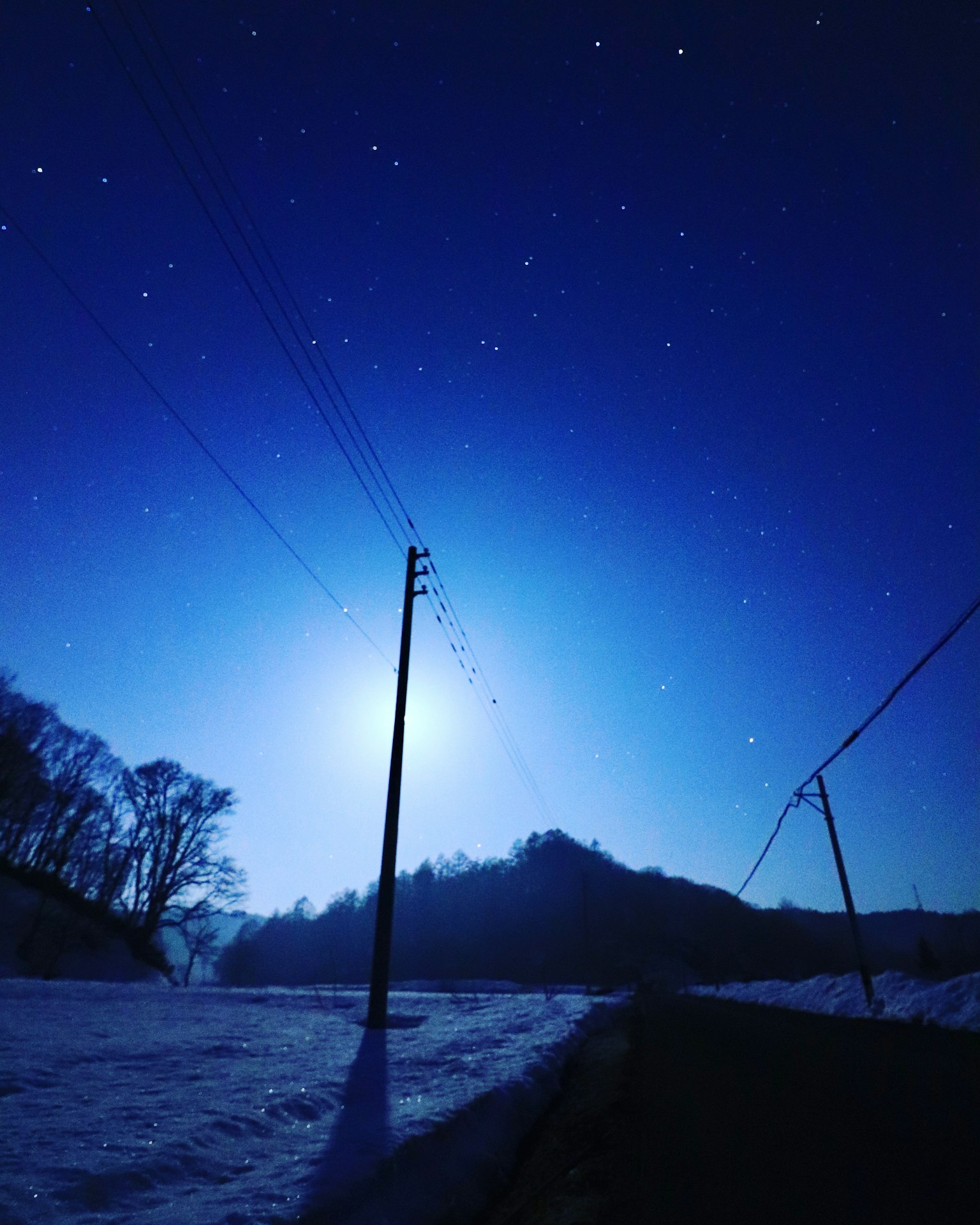 雪路在星空下,月光和电线照亮