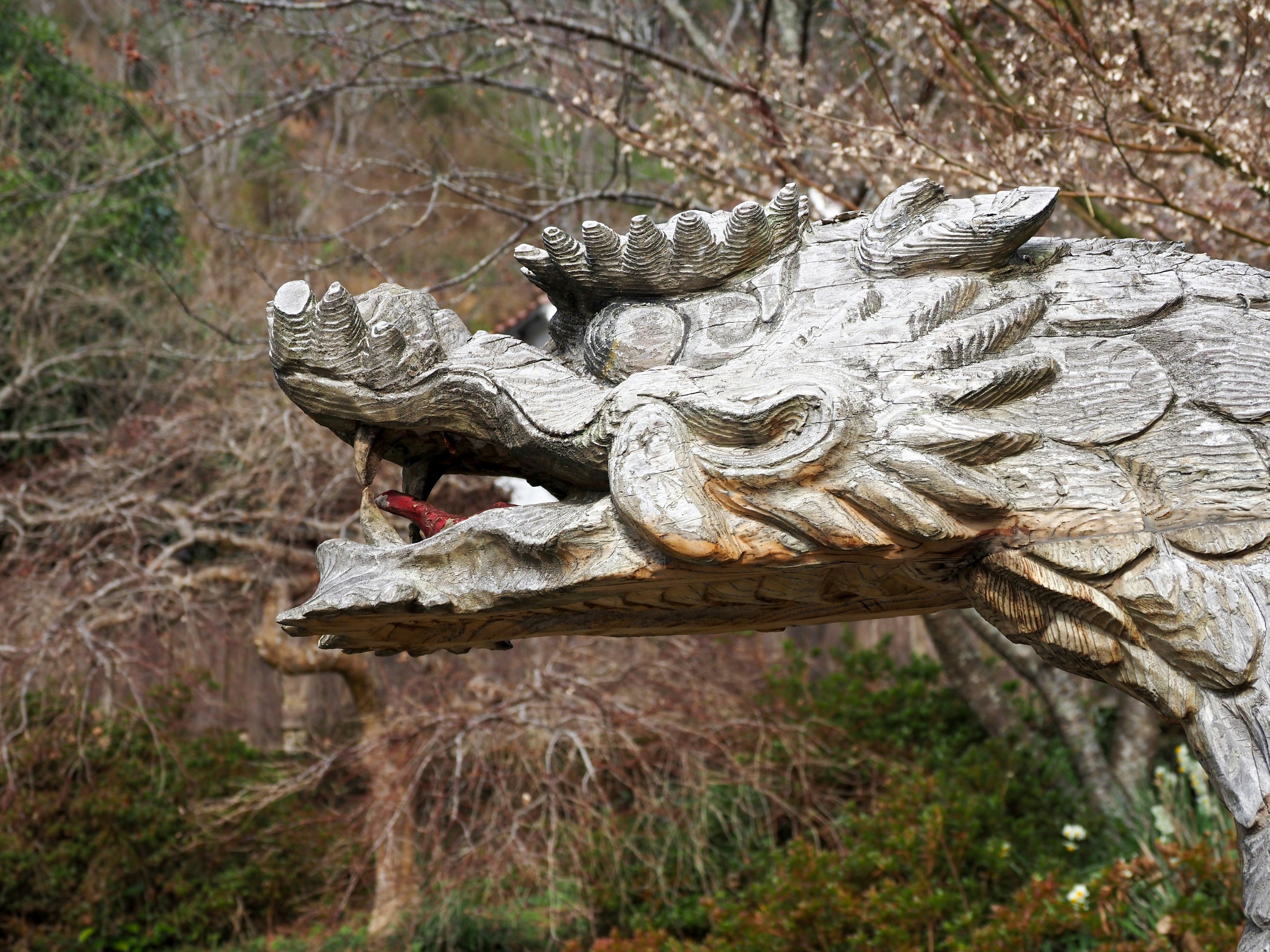翼の彫刻が乗った石像と鳥のモチーフのある庭園