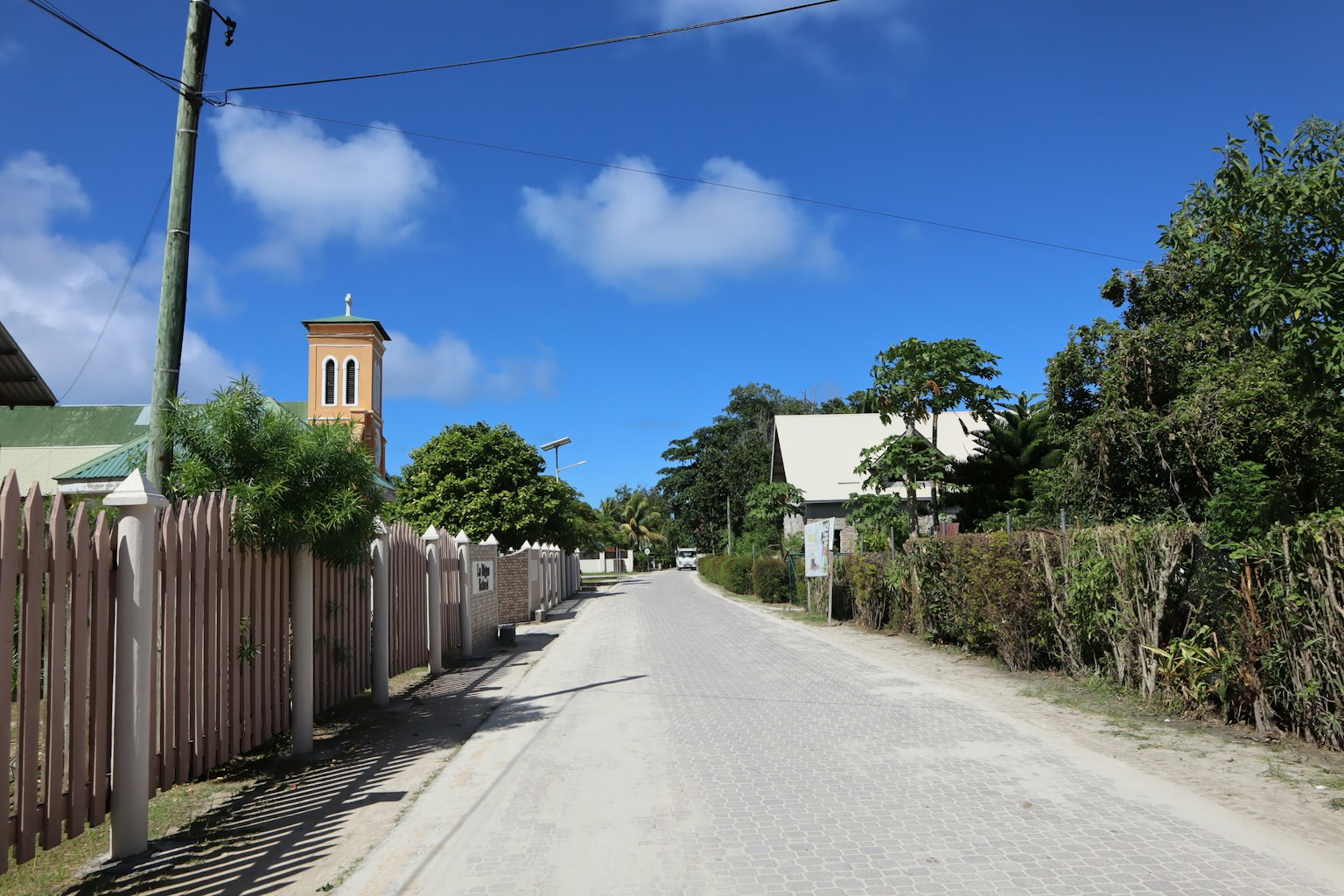 Rue tranquille avec des maisons et un clocher sous un ciel bleu