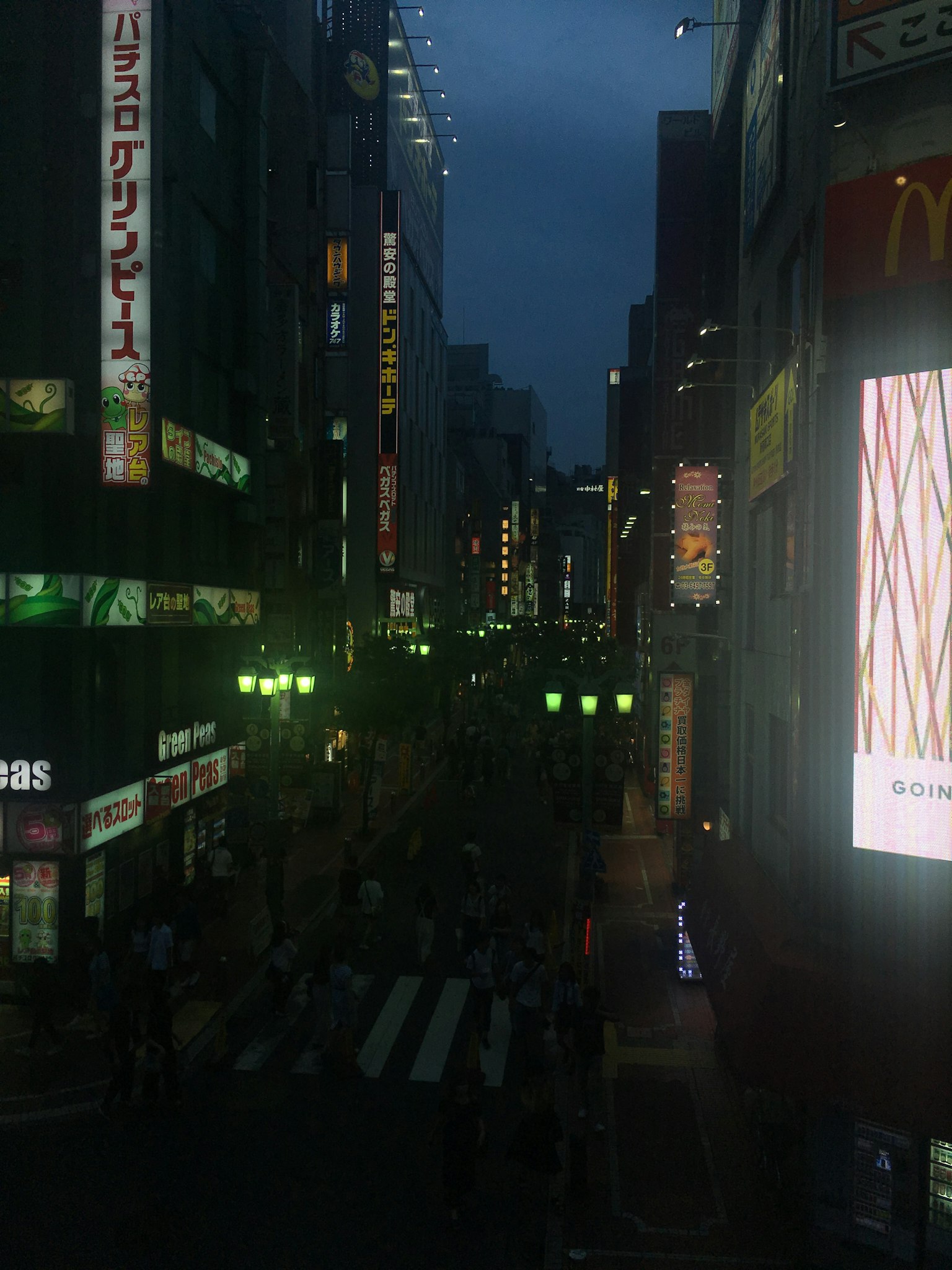 ทิวทัศน์ยามค่ำคืนของถนนที่คึกคักพร้อมป้ายไฟและคนเดินถนน