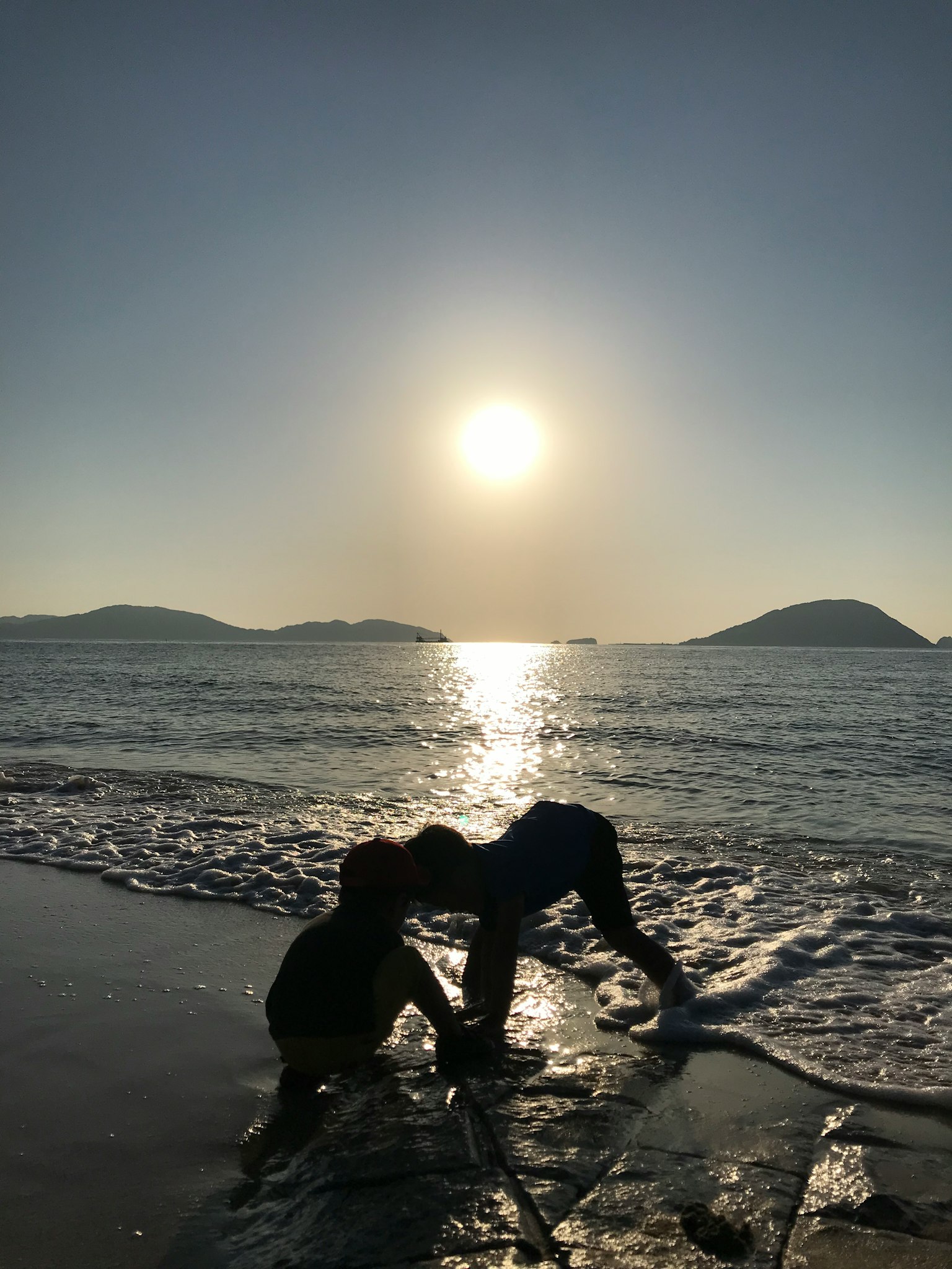 Bóng trẻ em chơi trên bãi biển với hoàng hôn