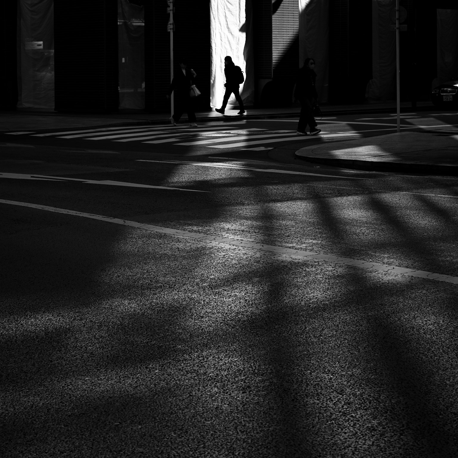 Silhouette di una persona che cammina in una strada cittadina con ombre incrociate