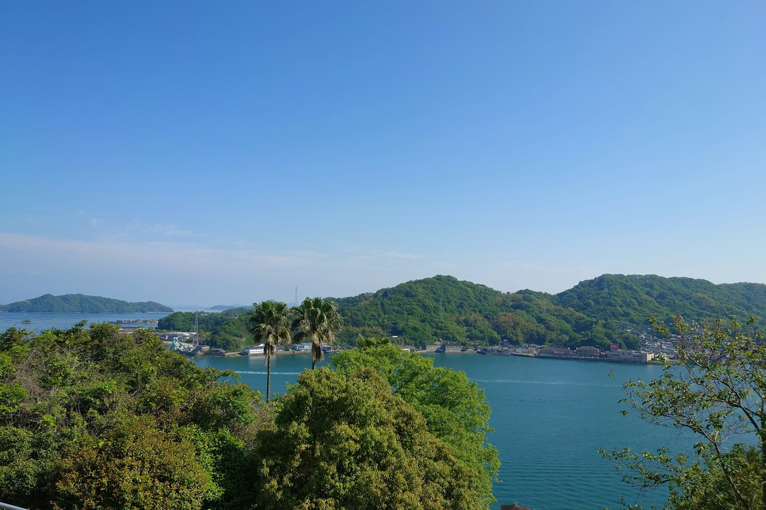 Pemandangan indah langit biru dan bukit hijau mengelilingi laut tenang