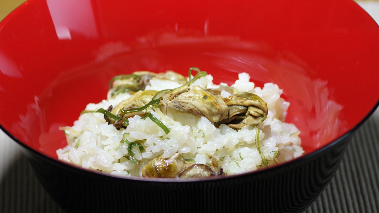 Riz blanc servi dans un bol rouge avec des garnitures d'herbes