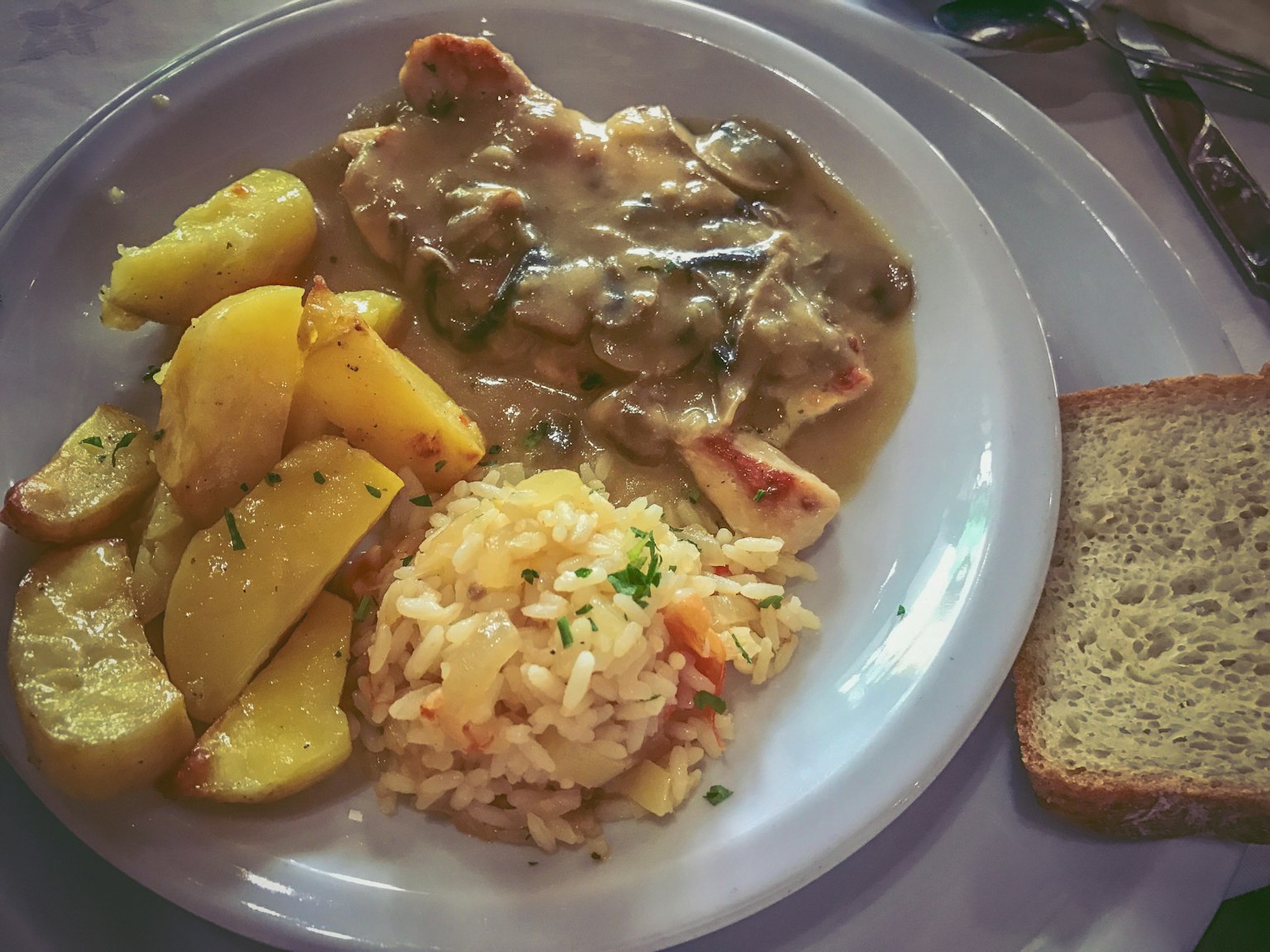 Plato de comida con pollo en salsa gravy con champiñones papas risotto y pan