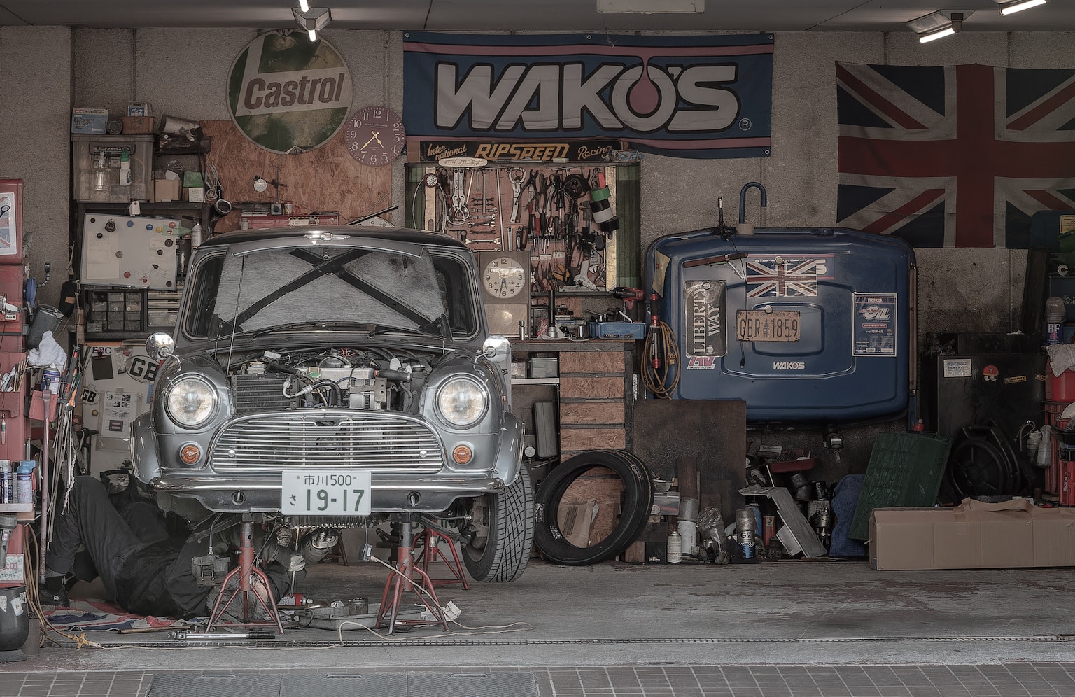 Ein Oldtimer wird in einer Garage mit verschiedenen Werkzeugen und Postern repariert