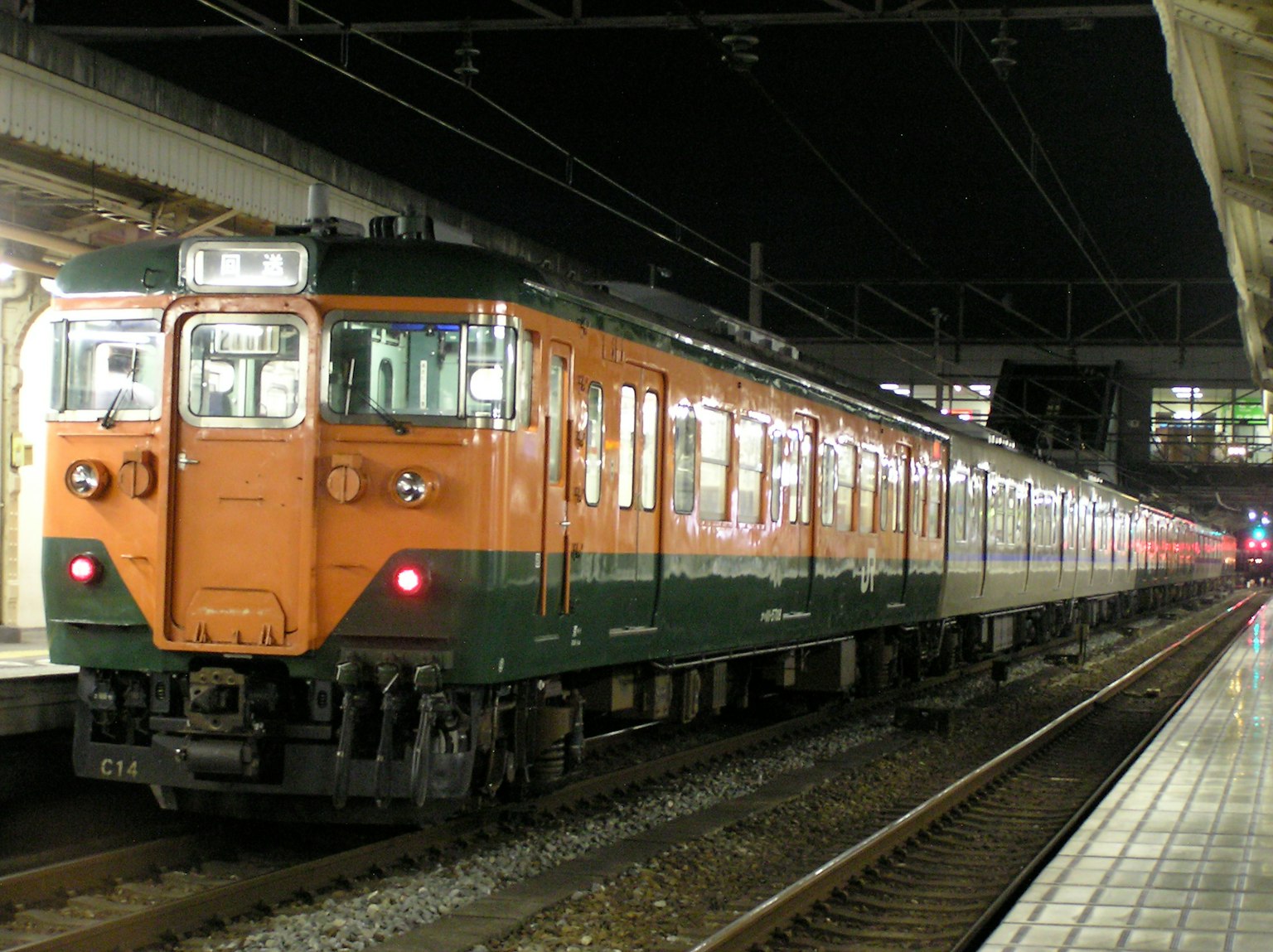 Treno arancione e verde fermo in stazione di notte