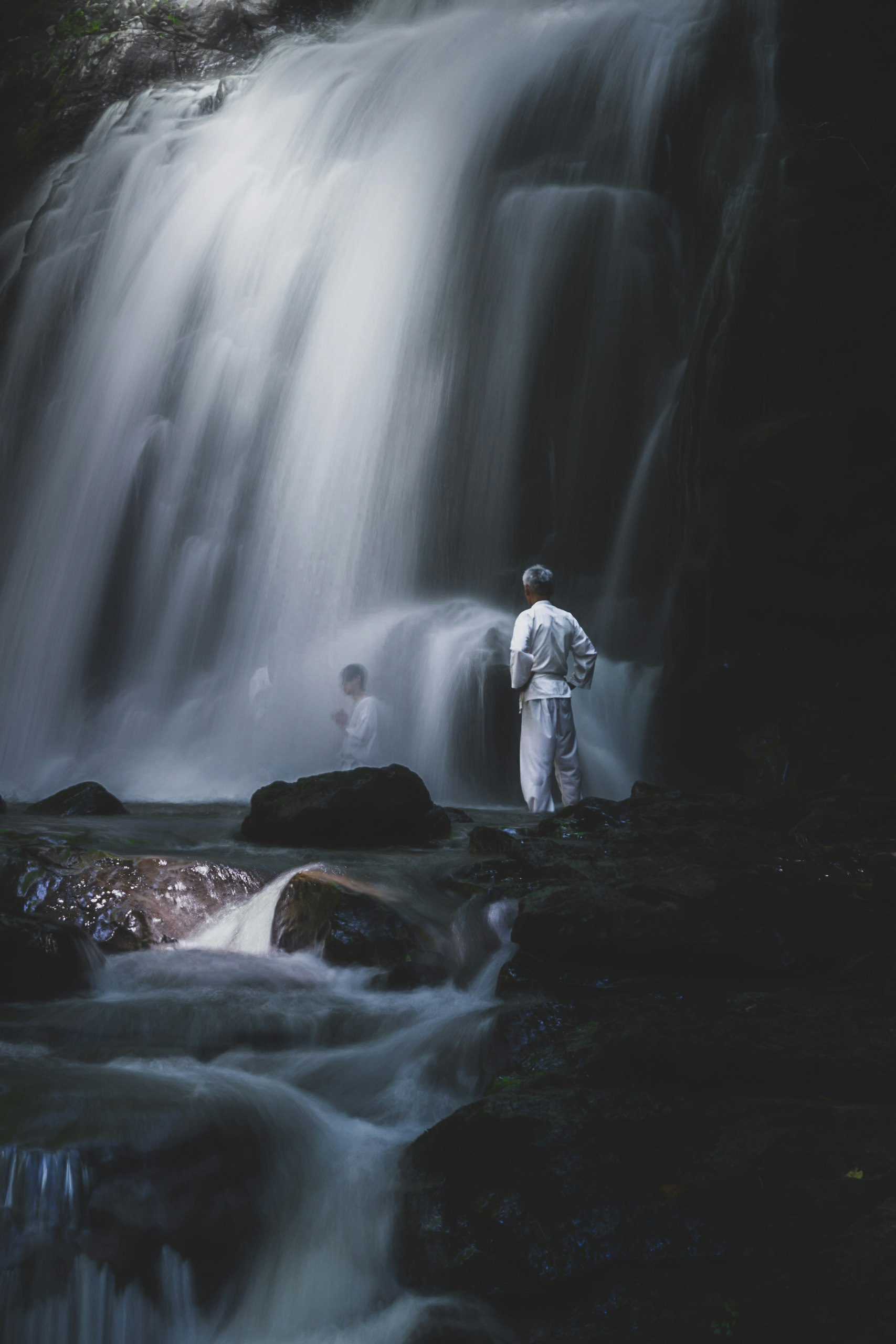 滝の前に立つ人物と流れる水の景観