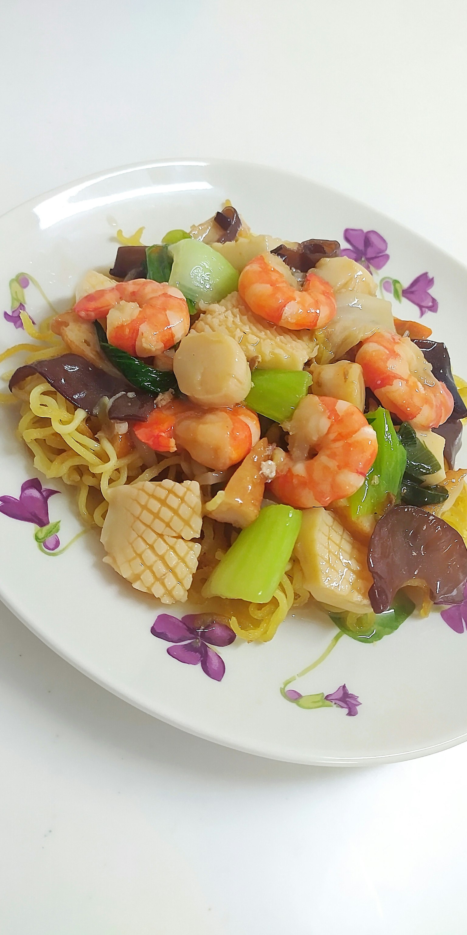 Verdure saltate con gamberi e pollo su noodles fritti