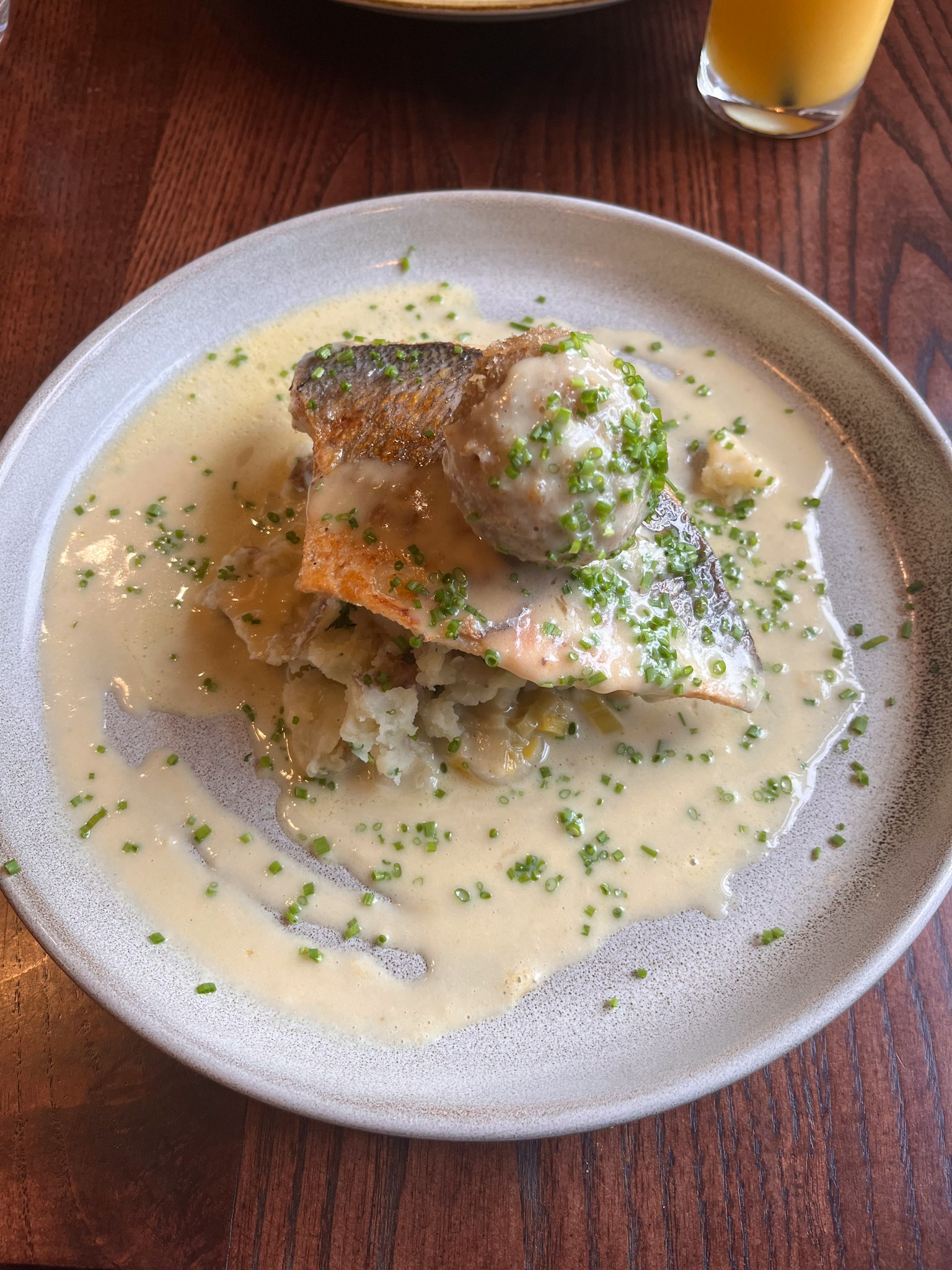 A dish featuring salmon with creamy sauce garnished with herbs