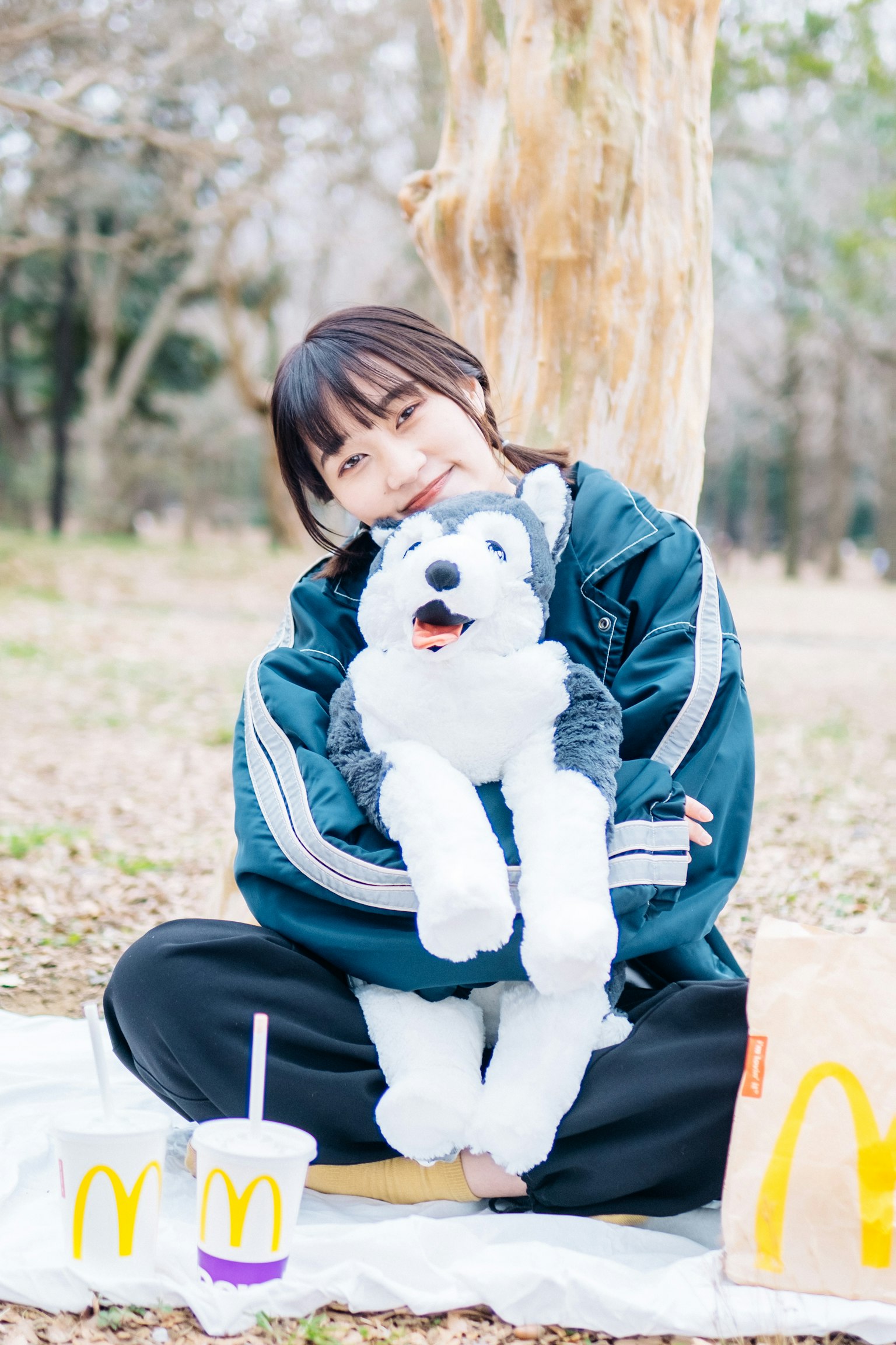 Una ragazza abbraccia un husky di peluche in un parco