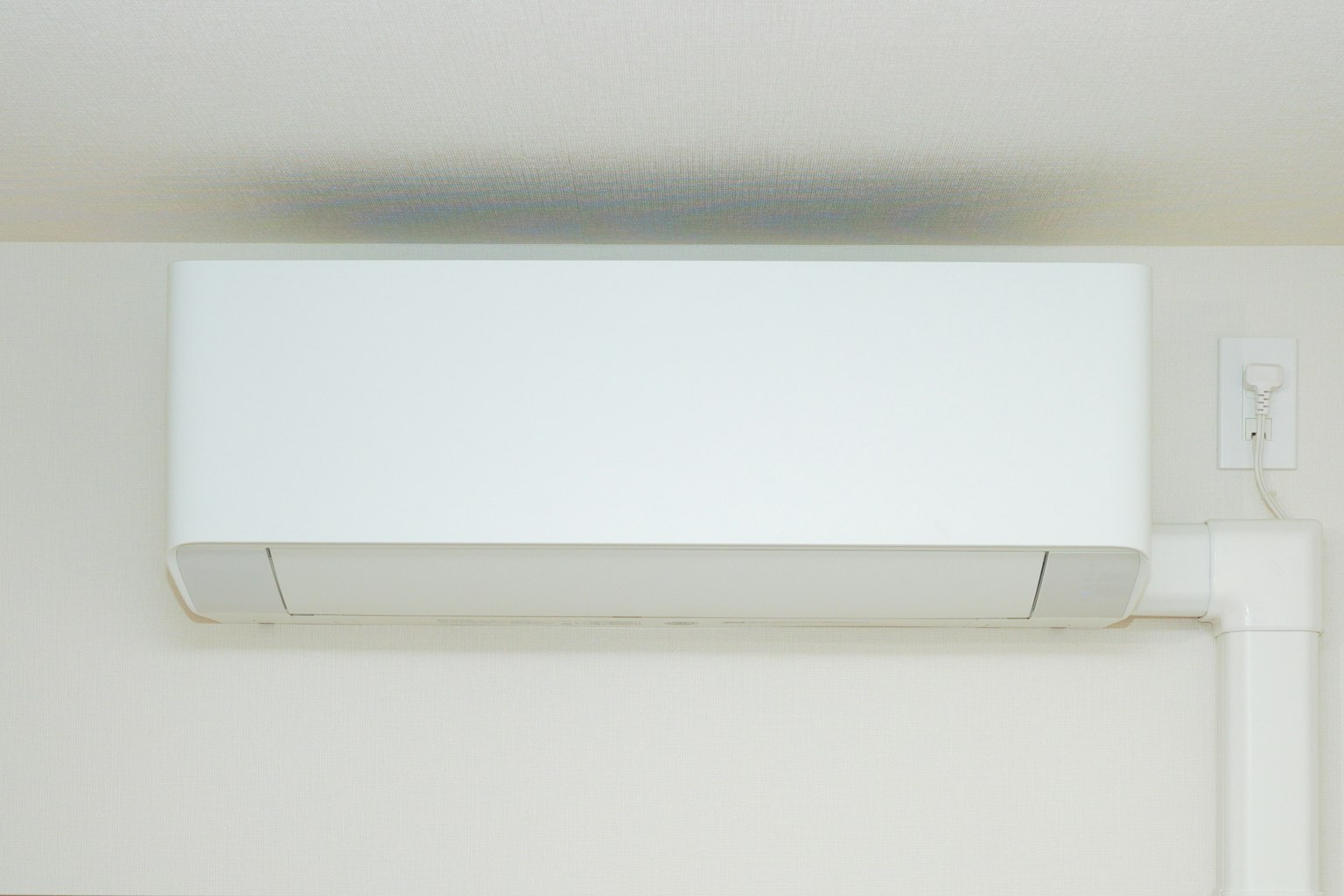 Un climatiseur blanc monté au plafond dans un cadre intérieur simple