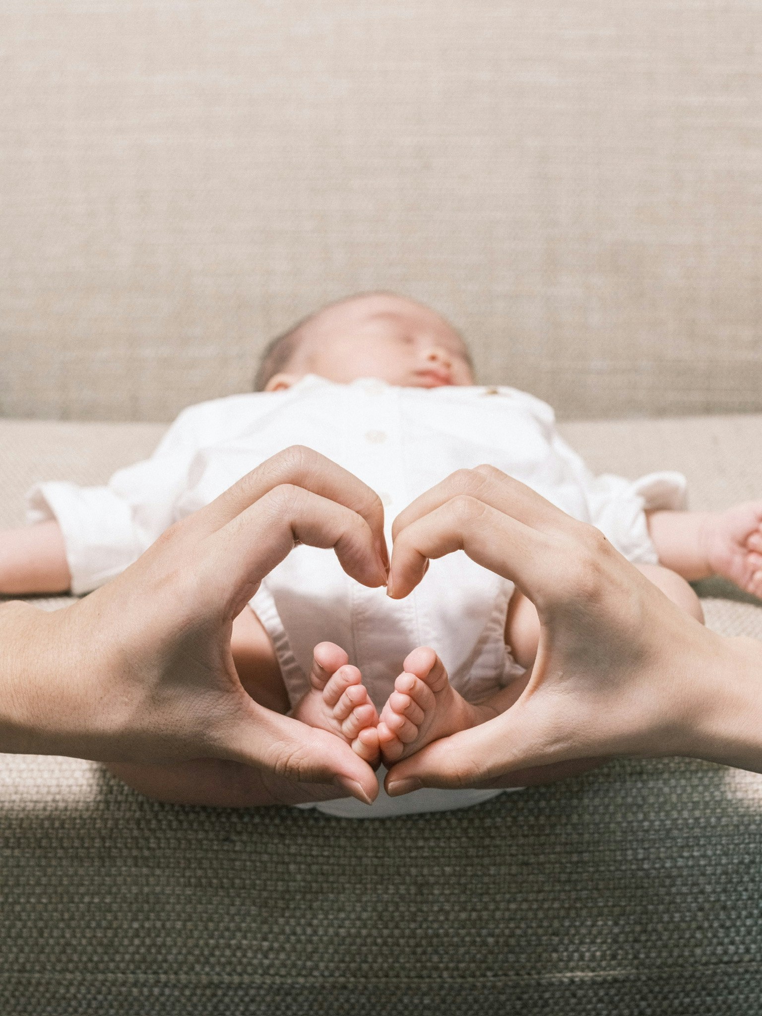 Tangan membentuk bentuk hati di sekitar bayi yang sedang tidur