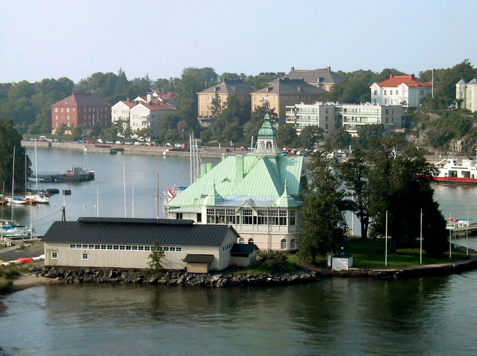 A green-roofed building by the harbor with surrounding colorful houses