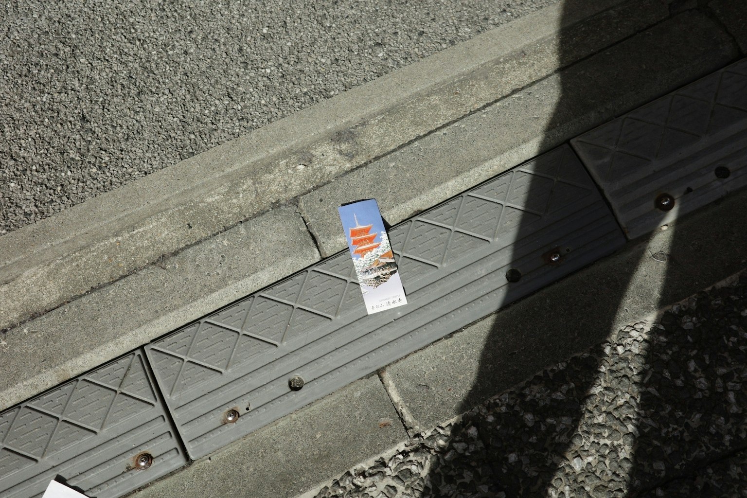 A small brochure lying on the sidewalk with a shadow
