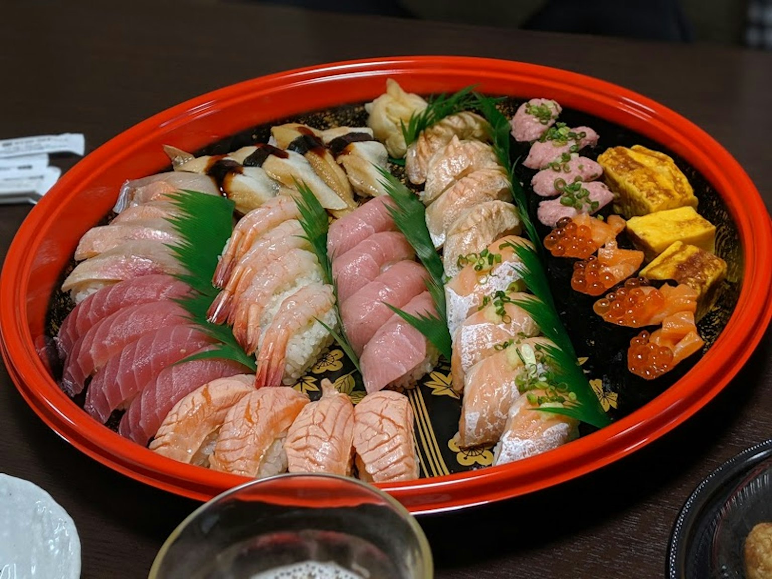 Sushi berwarna-warni disusun di atas piring merah