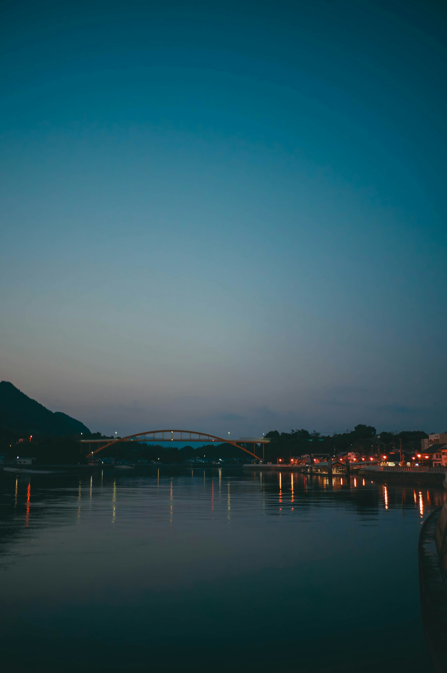 Escena de río al atardecer con silueta de un puente