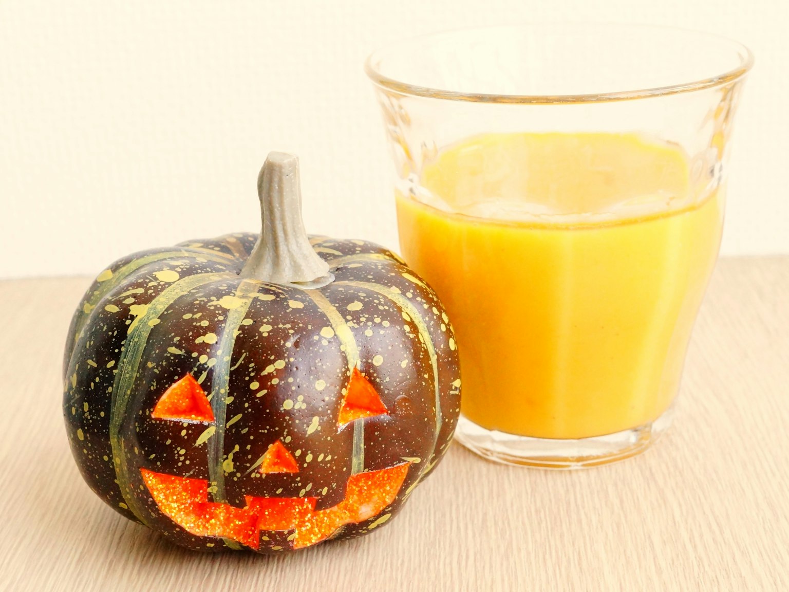 Bí ngô Halloween được khắc cạnh một ly nước cam