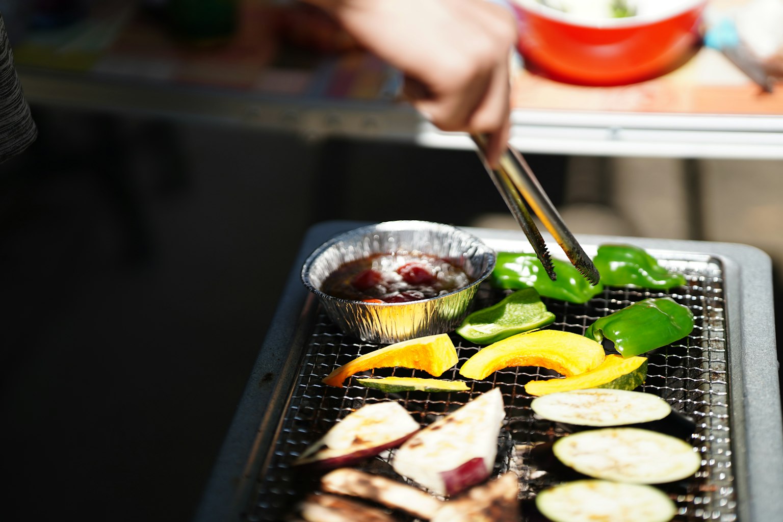 Nahaufnahme von Gemüse und Fleisch auf dem Grill mit Zangen