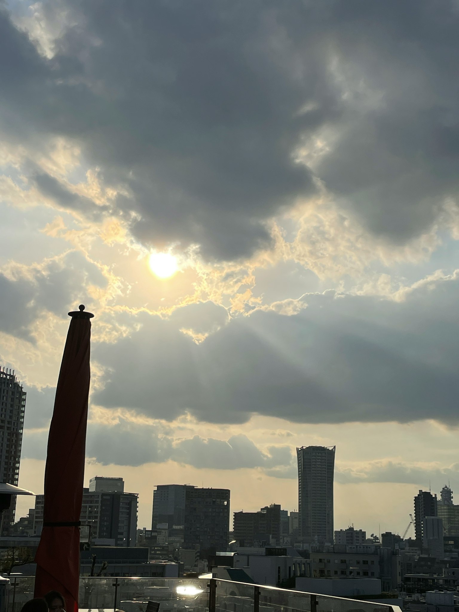 Sun setting behind clouds over a city skyline