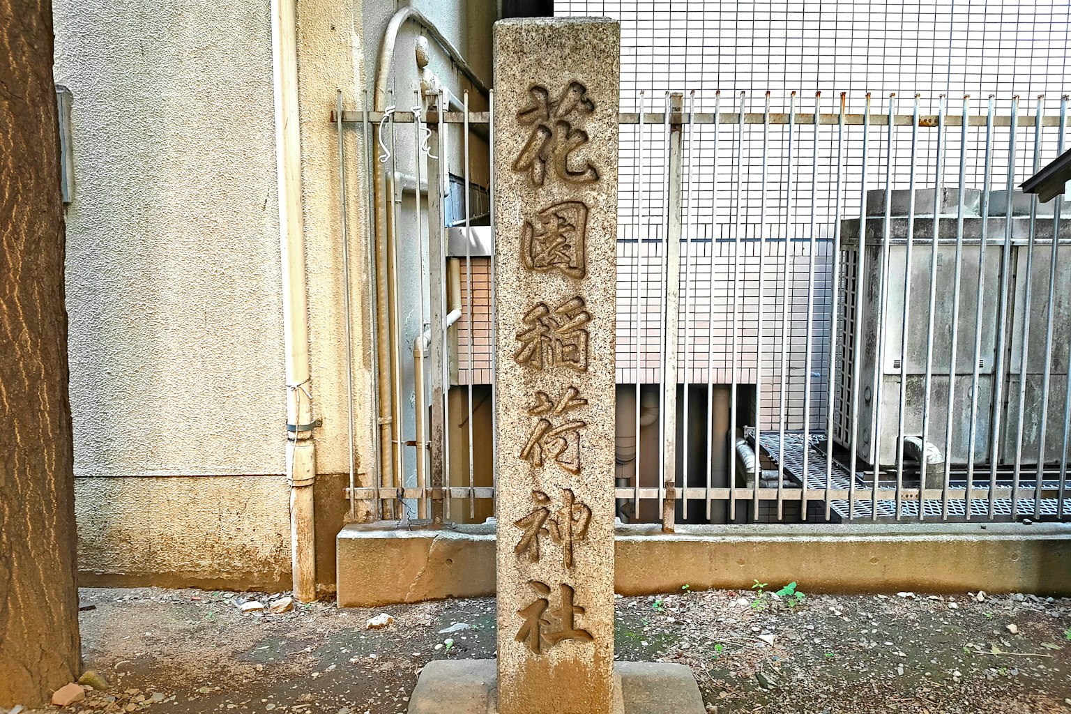 Monumento in pietra del santuario Hanazono con una recinzione metallica sullo sfondo