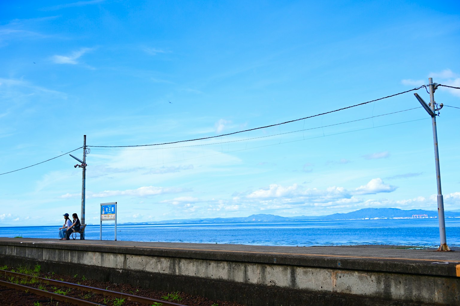People walking along a coastal path under a blue sky