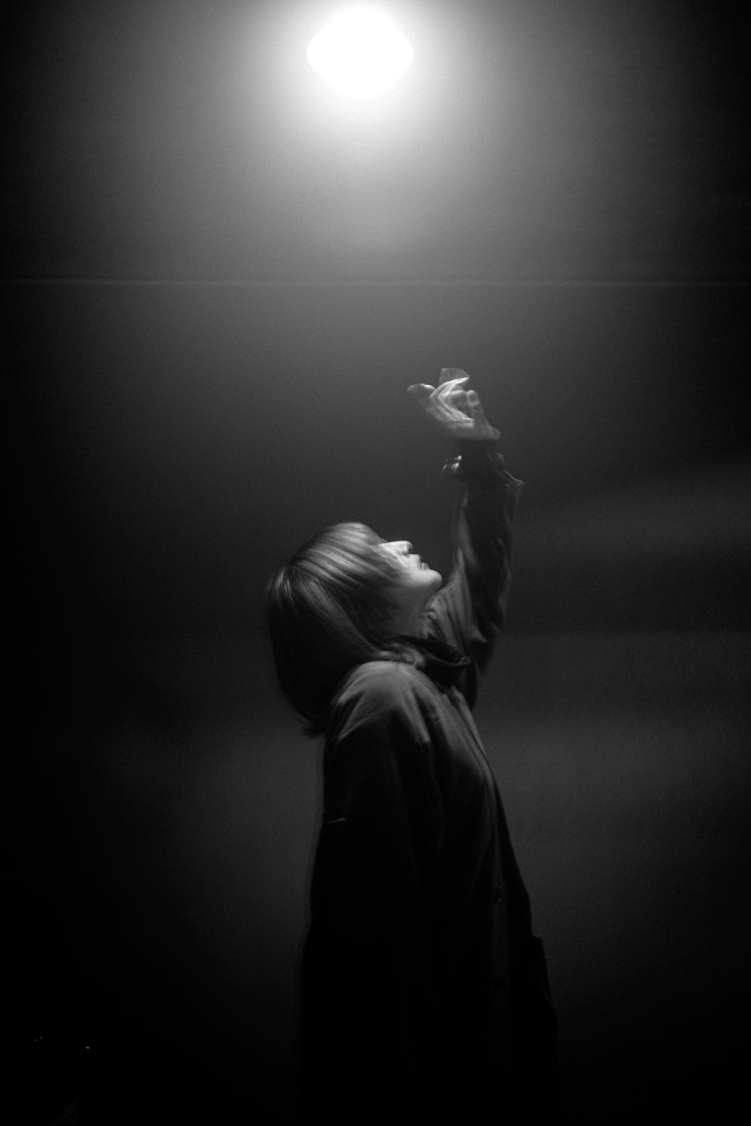 黒と白の写真で、人物が光を求めて手を伸ばしている