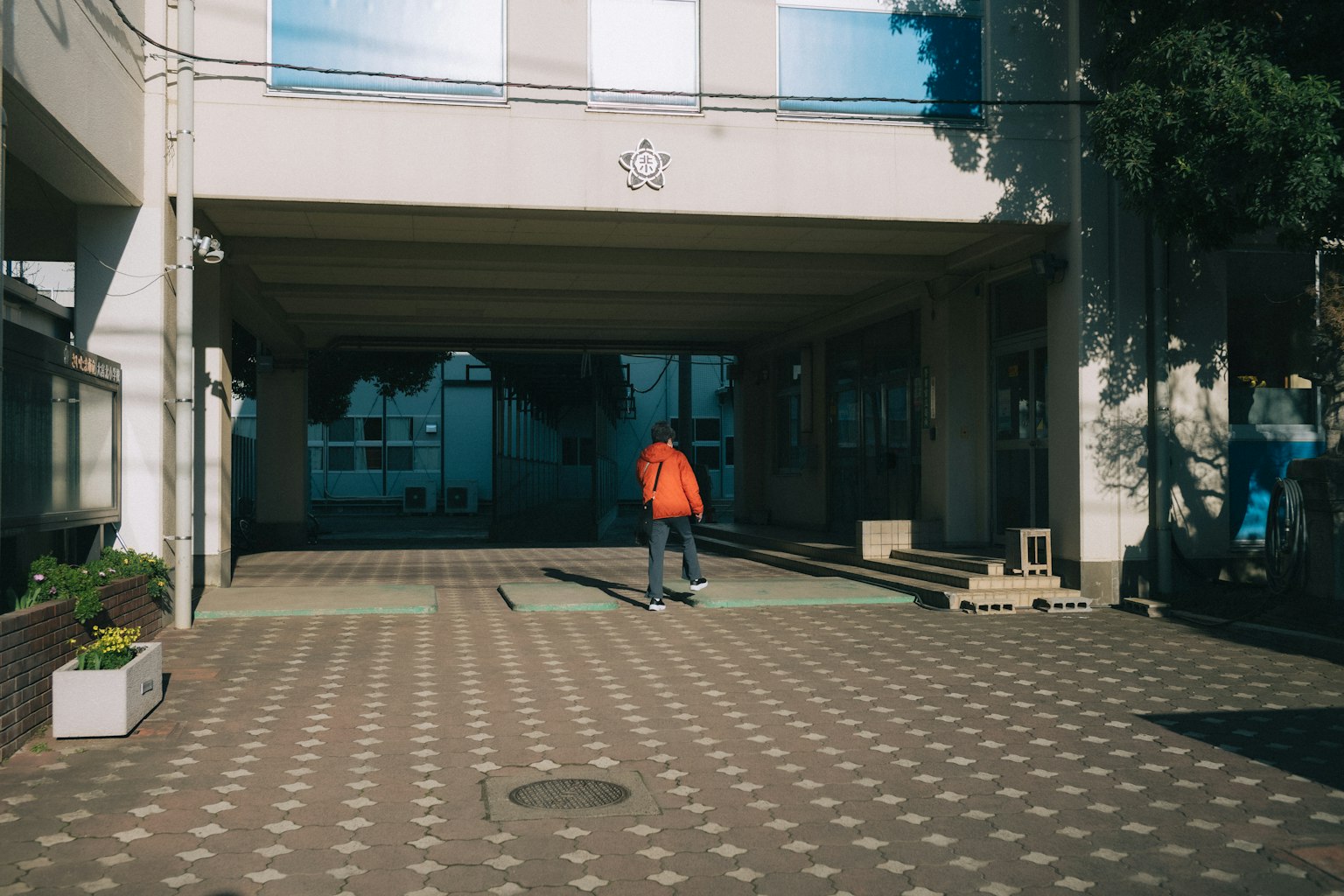 Una persona con ropa naranja caminando hacia la entrada de un edificio
